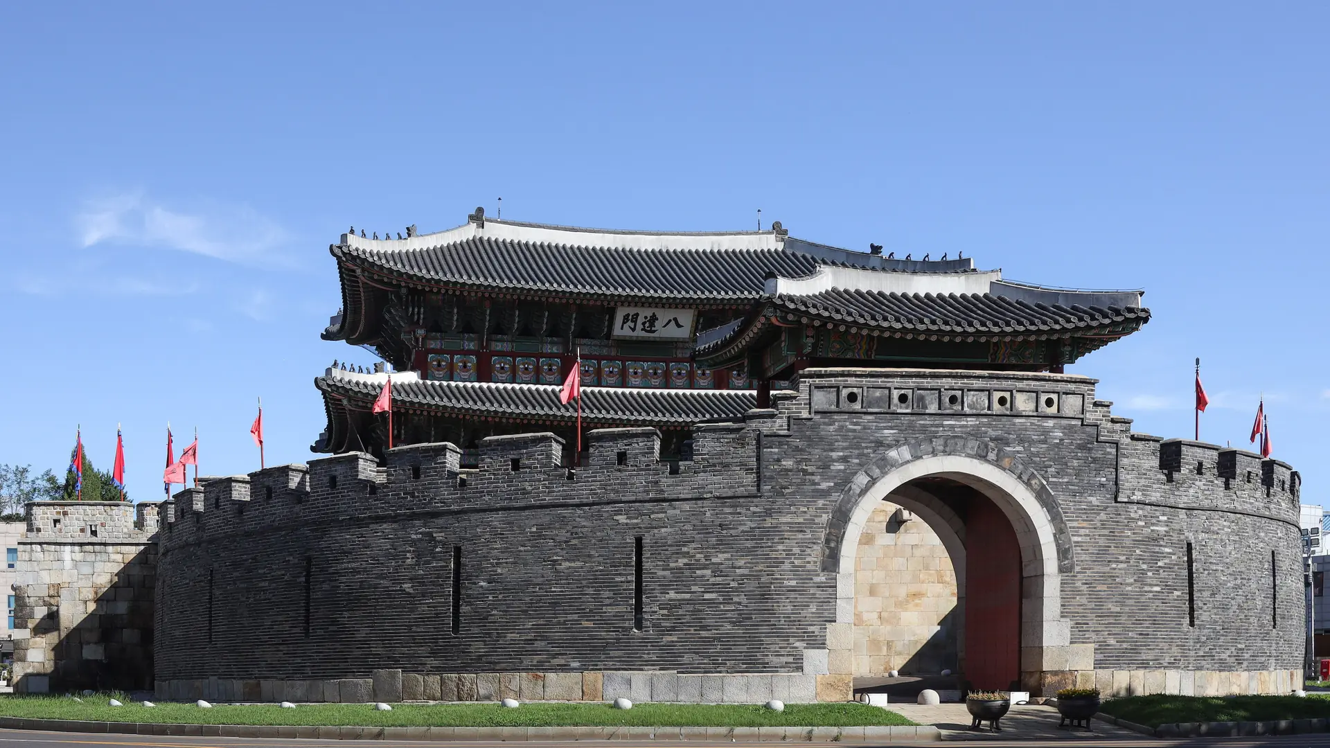 Paldalmun Gate's circular stone fortifications in Suwon, under a bright blue sky