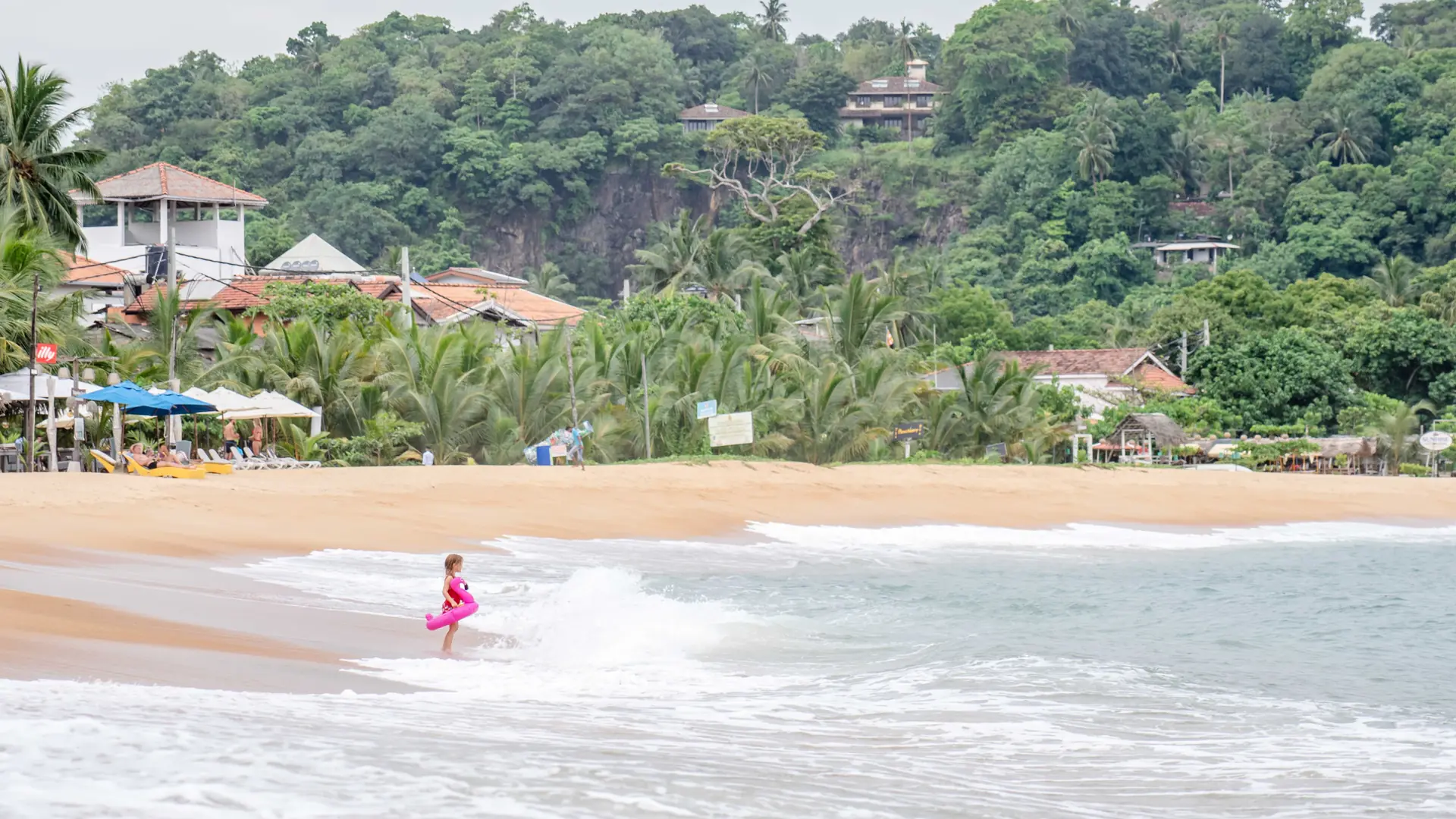 Child playing in gentle surf on a bright Sri Lankan beach