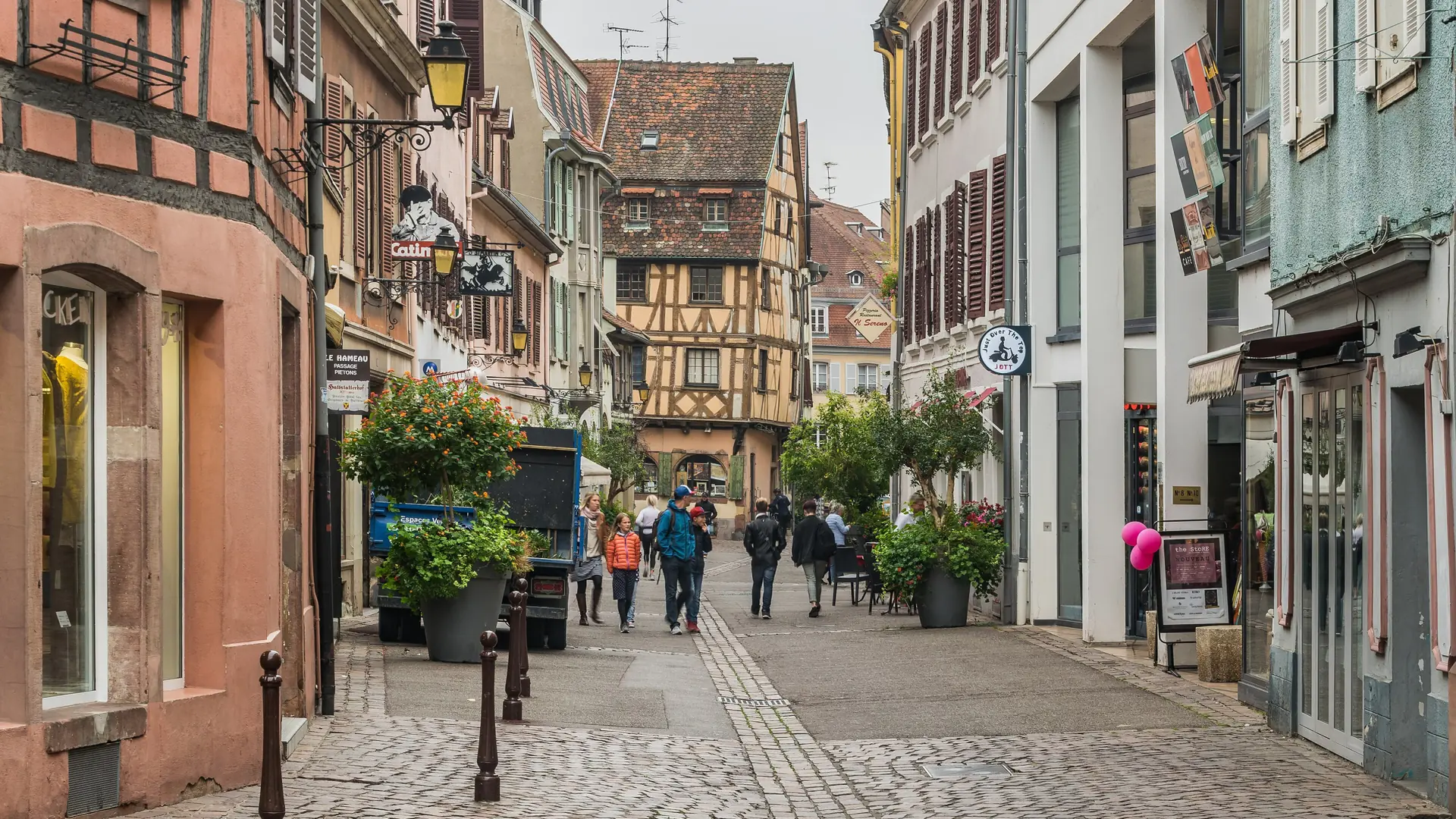 Shops, pedestrians and half-timbered houses on Rue des Marchands in Colmar