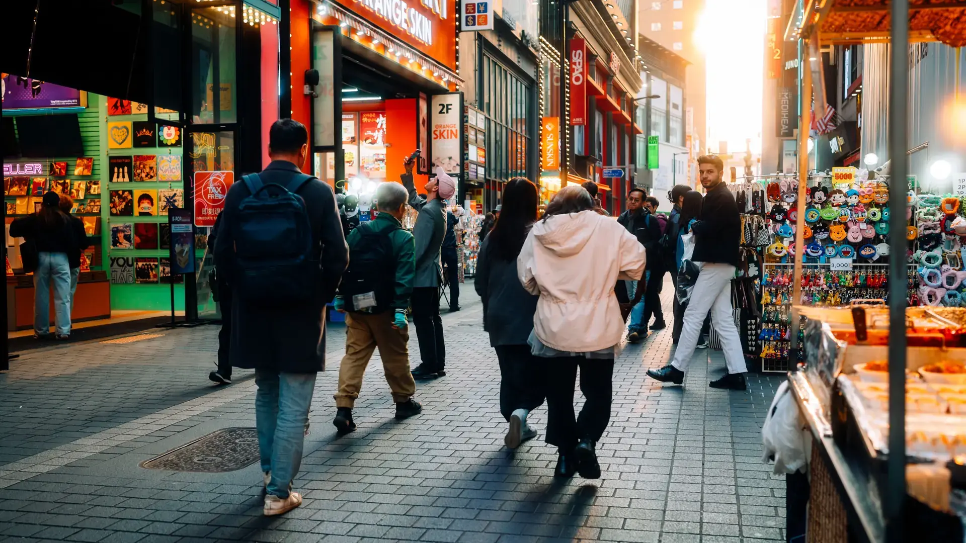 A lively Myeongdong shopping street in Seoul lit by storefront signs at dusk