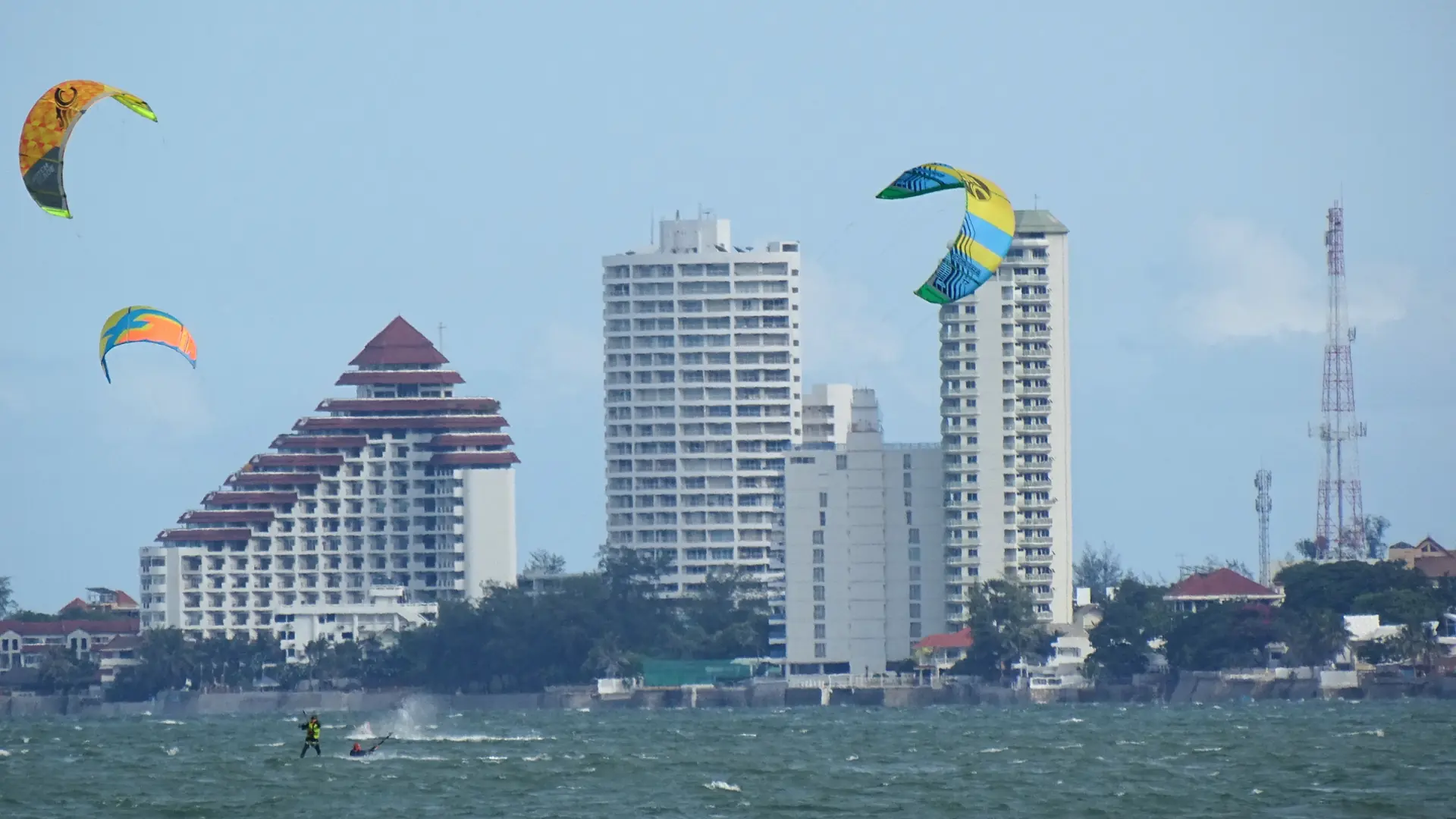Kitesurfers crossing Hua Hin's broad beach in front of the resort skyline