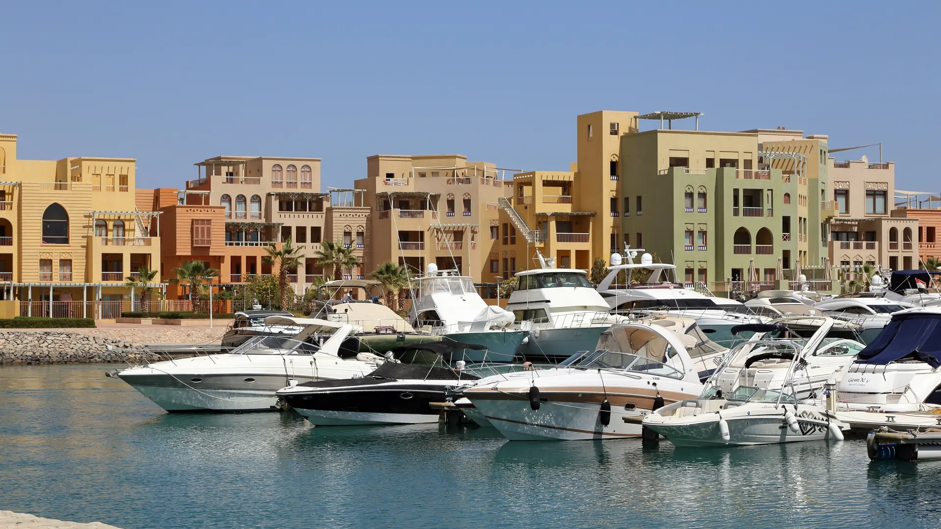 Sunlit New Marina in El Gouna, with yachts and sandy-coloured waterfront buildings