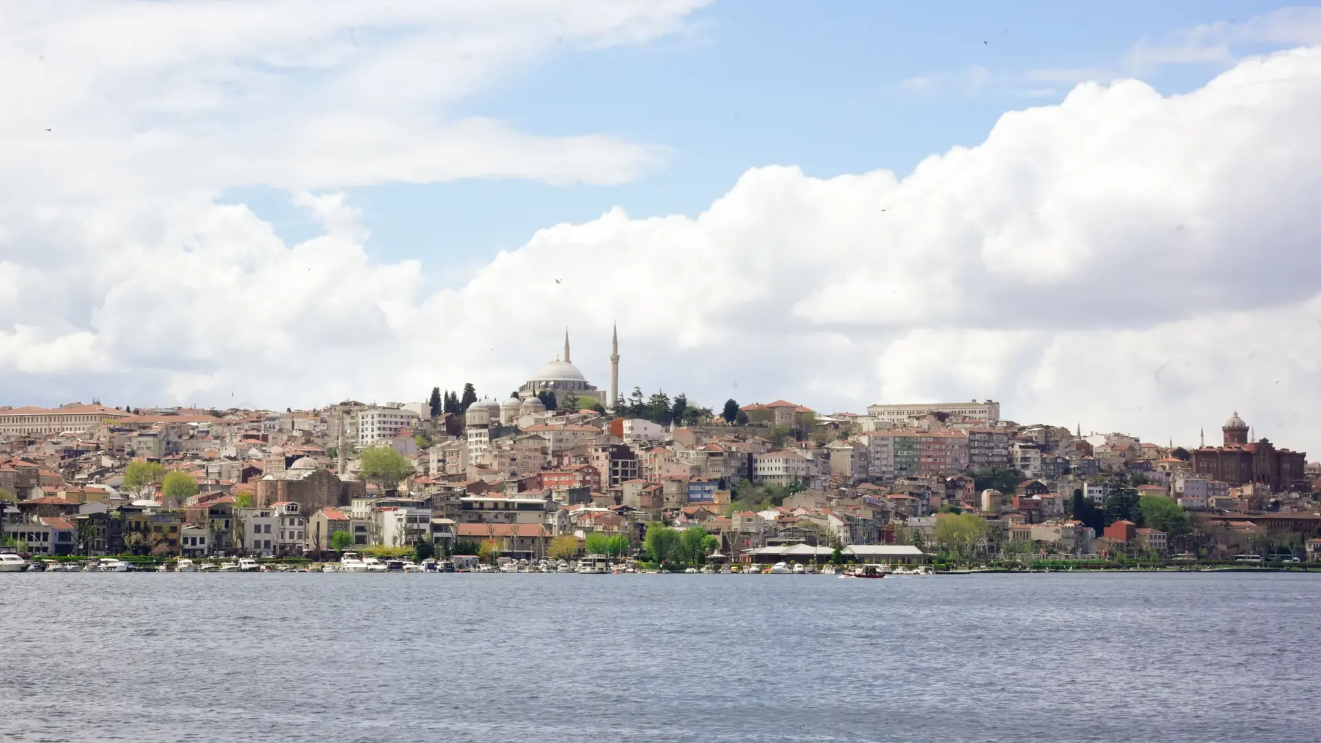 Istanbul mosque domes and waterfront beneath a broad cloudy sky