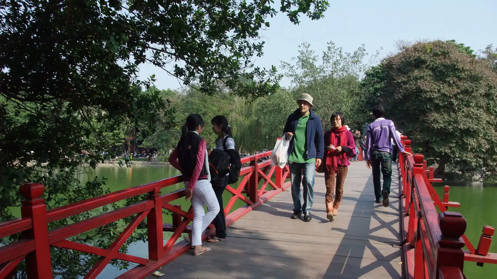 Visitors crossing the red The Huc Bridge over Hoan Kiem Lake in Hanoi.