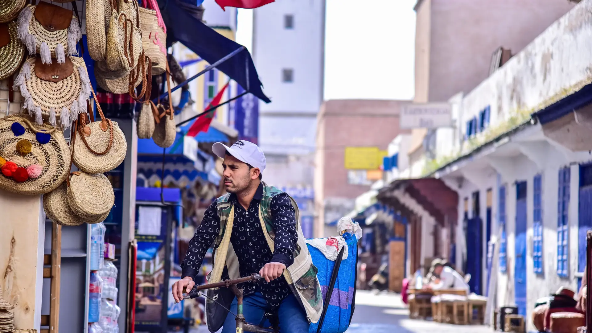 Cyclist passing blue shopfronts in Essaouira’s medina in daylight