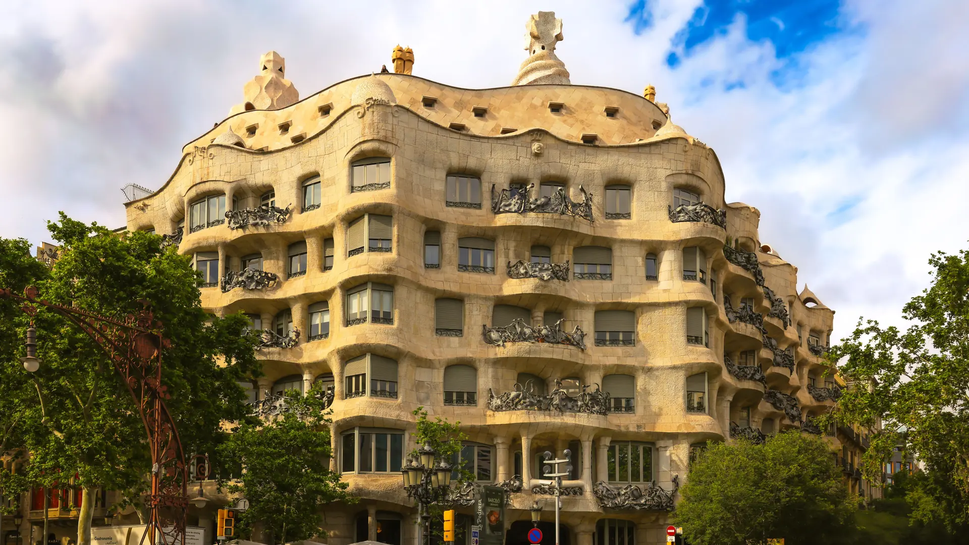 Casa Milà’s curved stone façade beside leafy Passeig de Gràcia in Barcelona’s Eixample