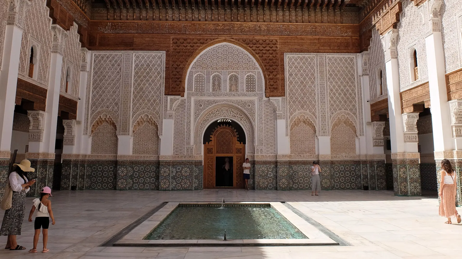 Carved arches, patterned tiles and the courtyard pool at Ben Youssef Madrasa in Marrakech