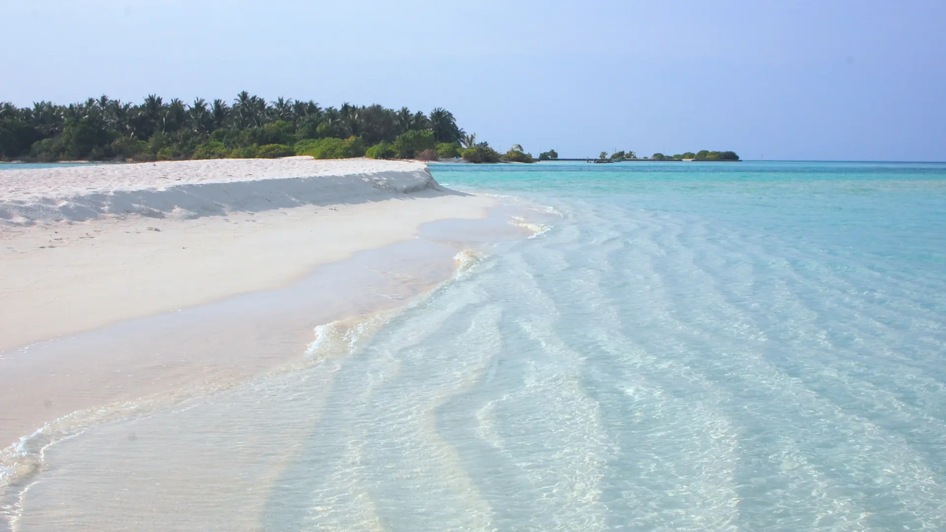 Sunlit sand and shallow lagoon near neighbouring Mathiveri in North Ari Atoll
