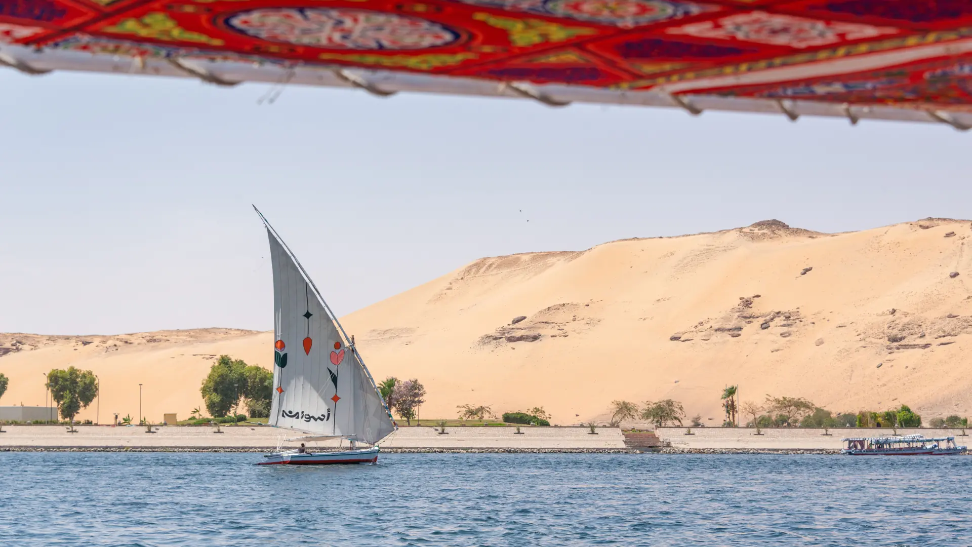 White felucca crossing the Nile beside a sandy bank at Aswan
