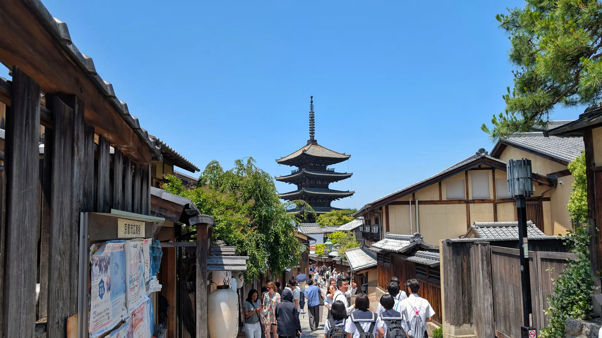 Yasaka Pagoda above wooden houses and visitors on a sunlit Higashiyama street in Kyoto
