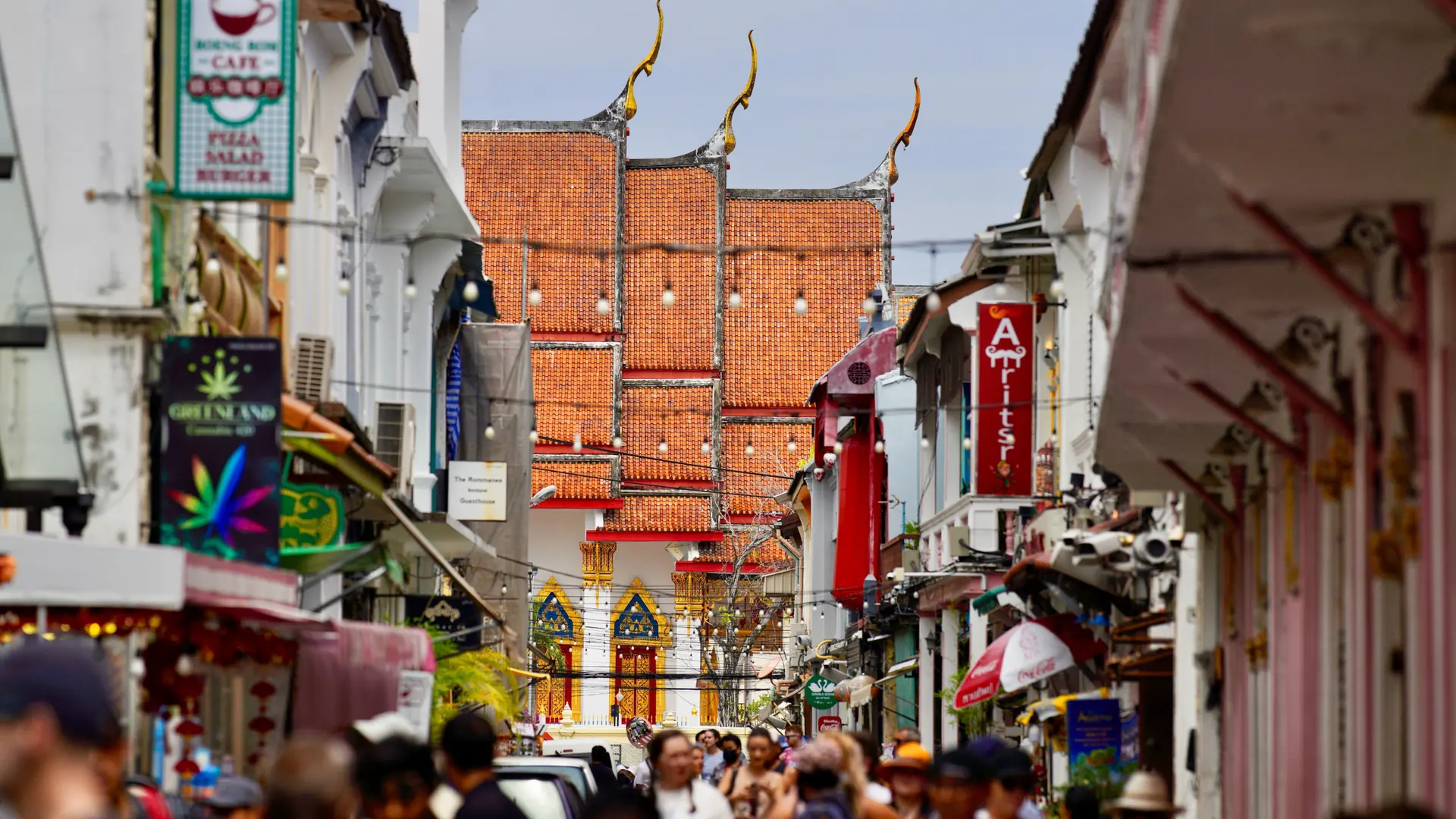 Tourists walking between colourful traditional shopfronts in Phuket Town