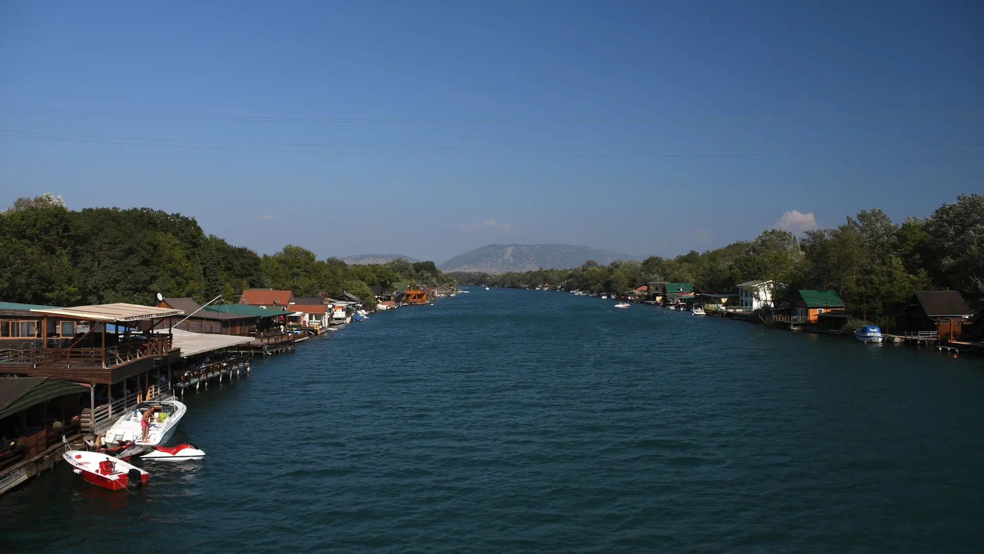 Bojana River between wooden riverside houses near Ada Bojana under a blue sky