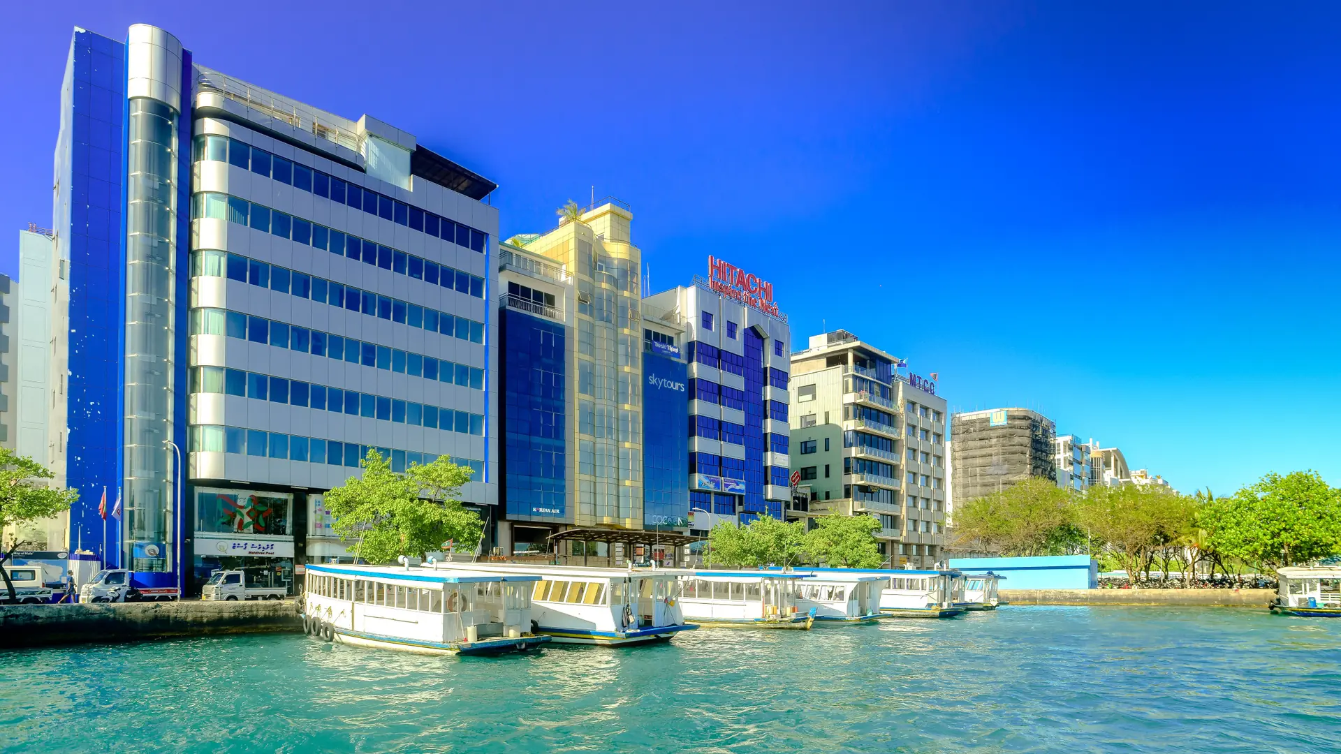 Sunlit modern buildings along the Malé city waterfront, seen across the water