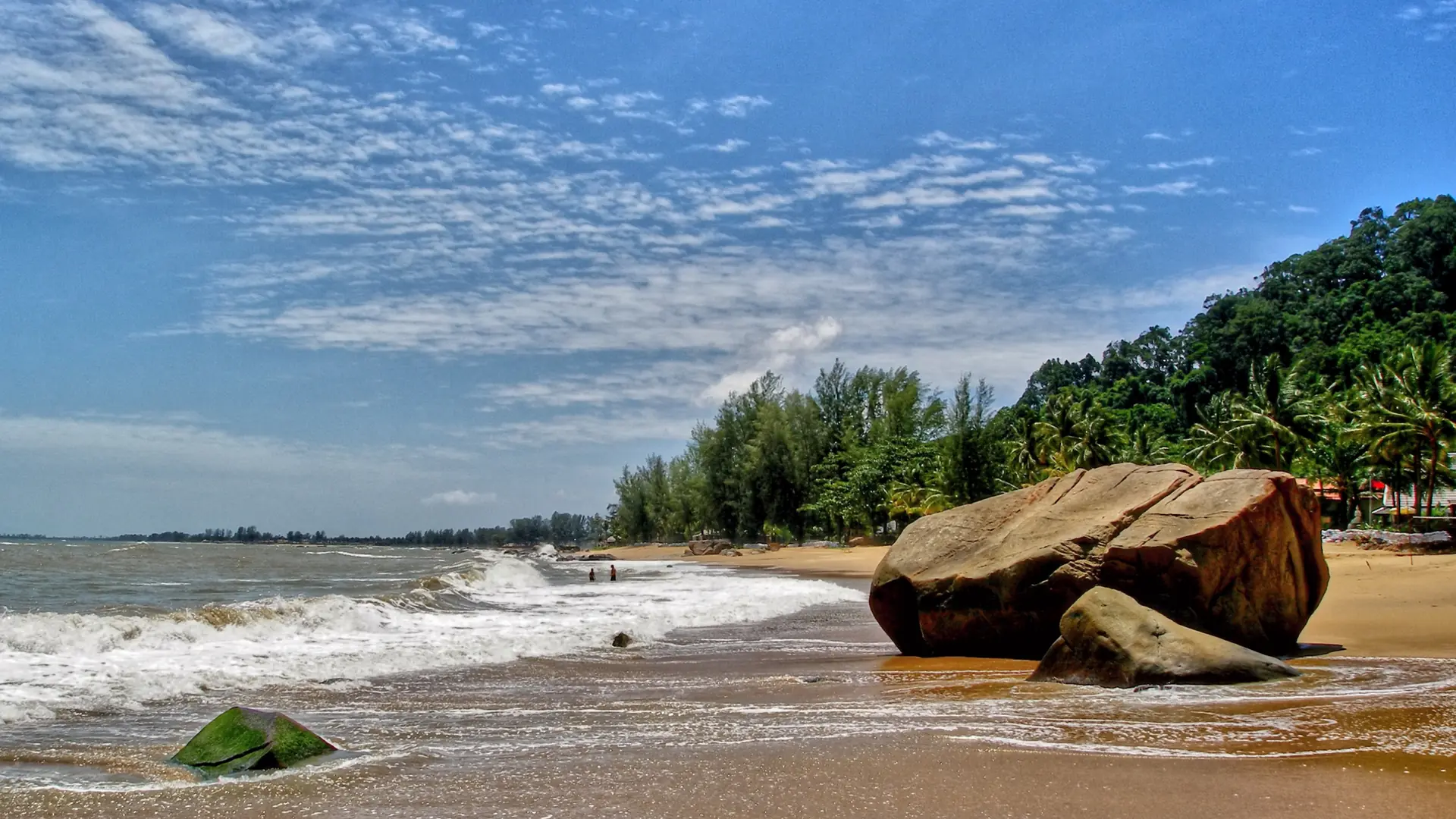 A spacious Khao Lak beach backed by dense tropical greenery