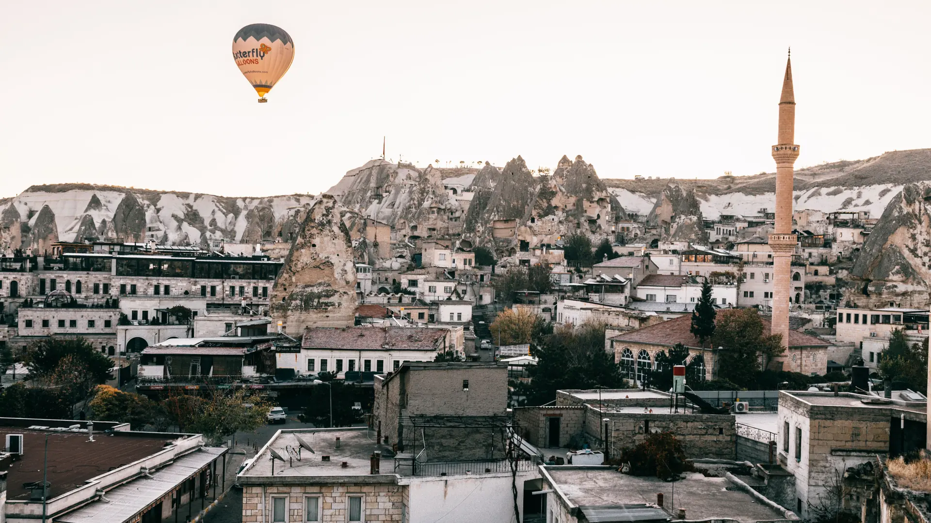 Göreme village among fairy chimneys with balloons in the sunlit sky