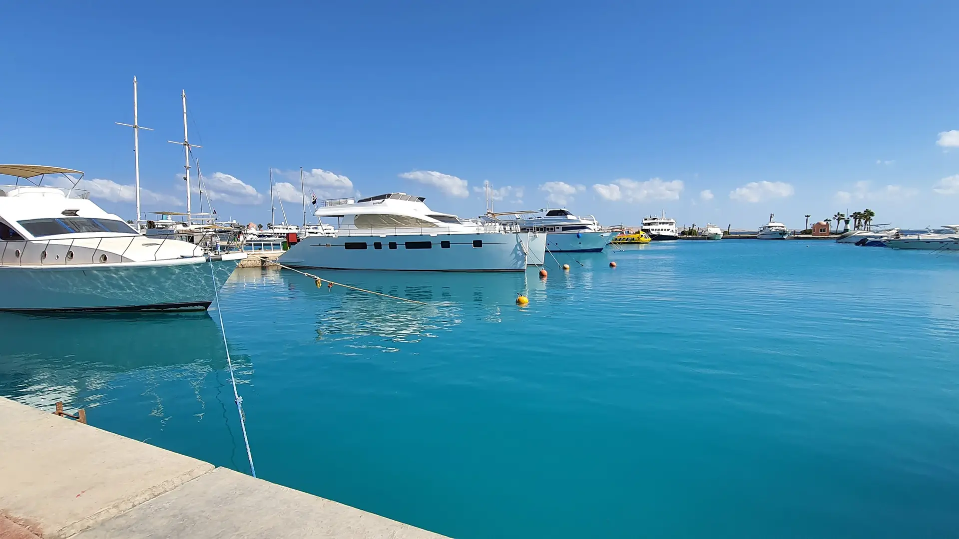 White yachts moored in Hurghada Marina beside turquoise water under a bright blue daytime sky.