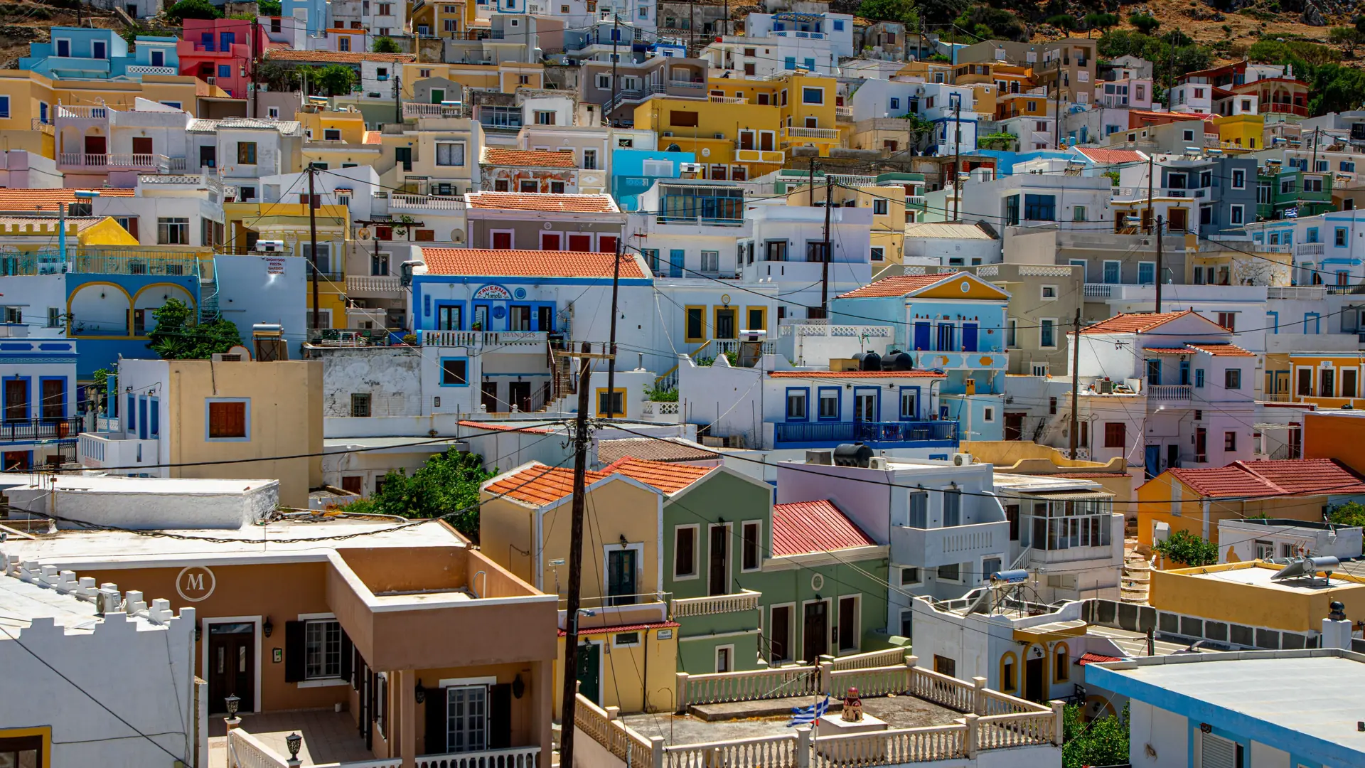 Colourful neoclassical houses climbing the steep hillside above Symi harbour