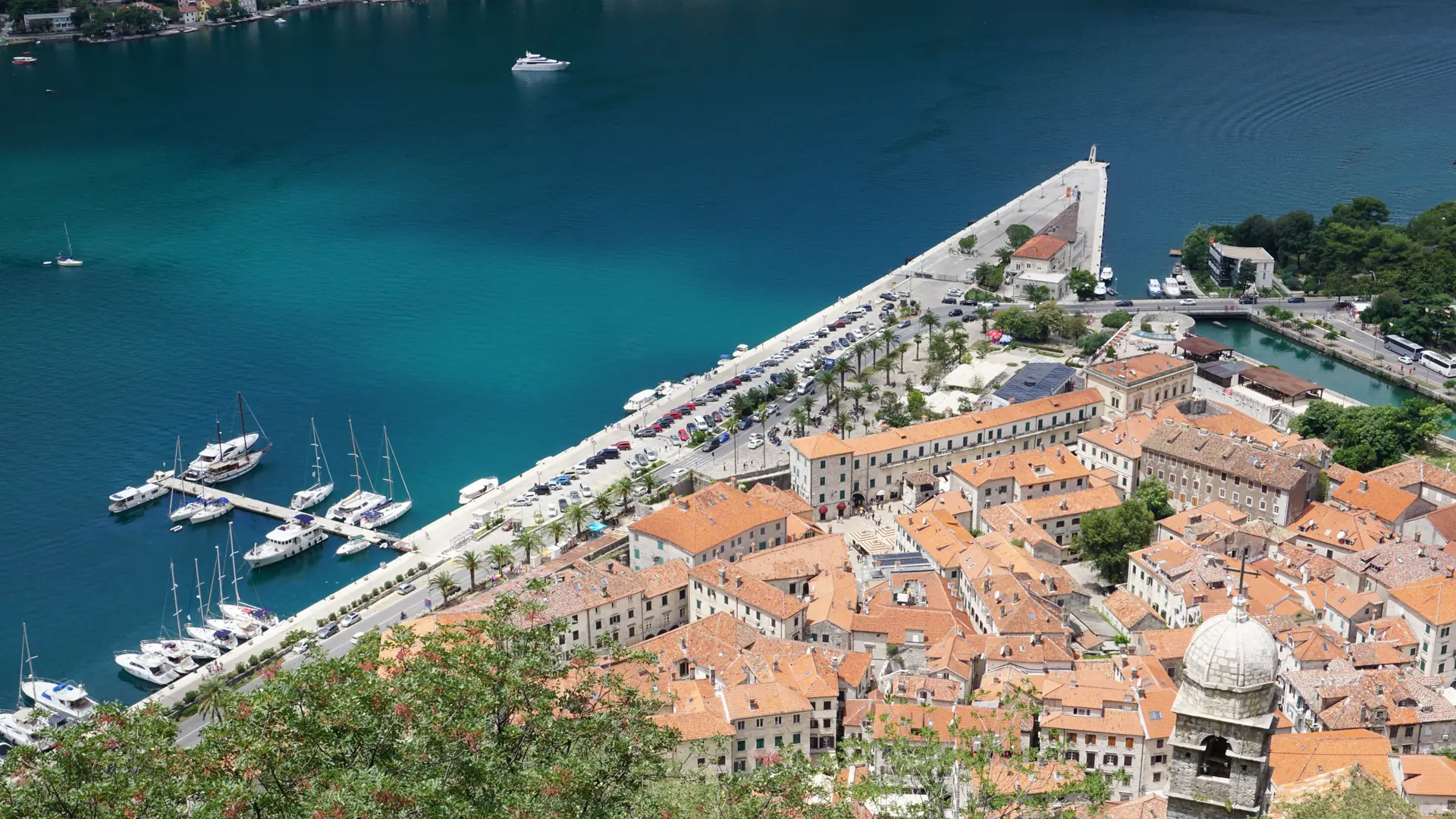 Kotor Old Town rooftops beside the blue inner bay in bright daylight