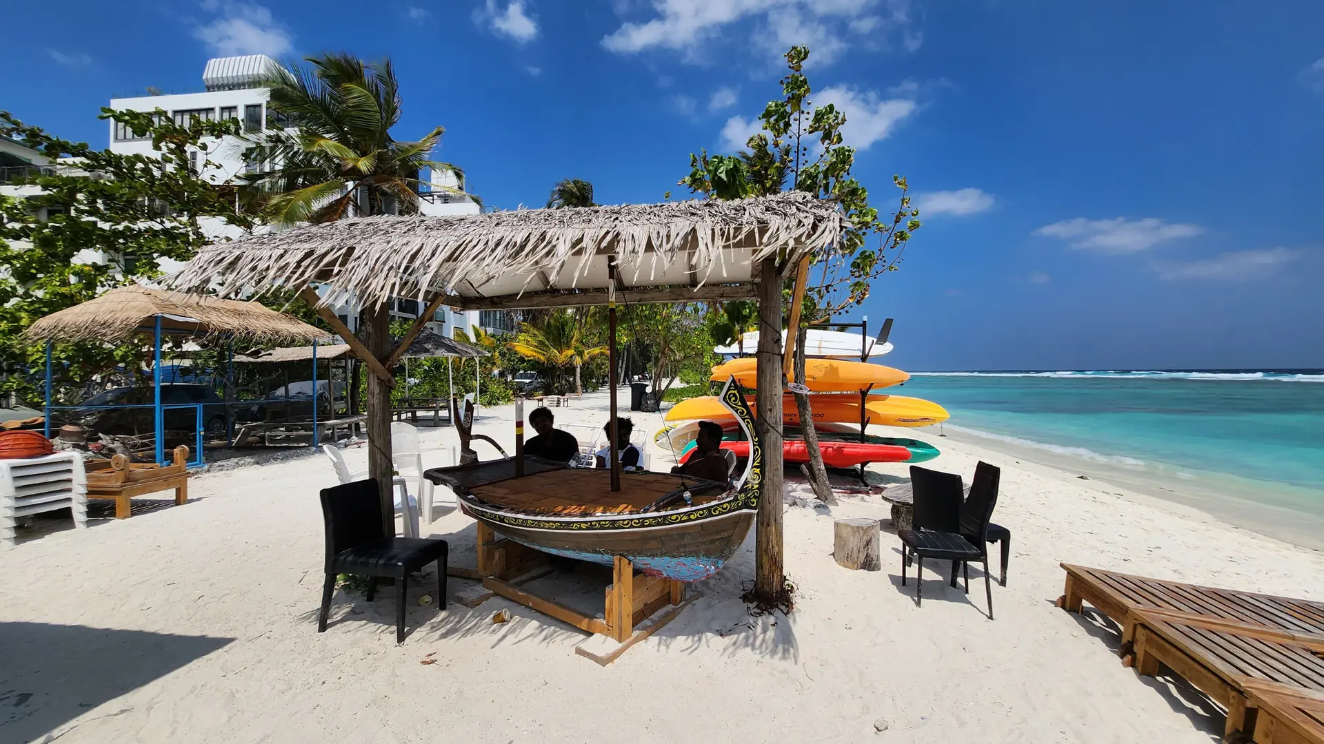 Sunlit Hulhumalé beachfront with sand, sea and the city behind it
