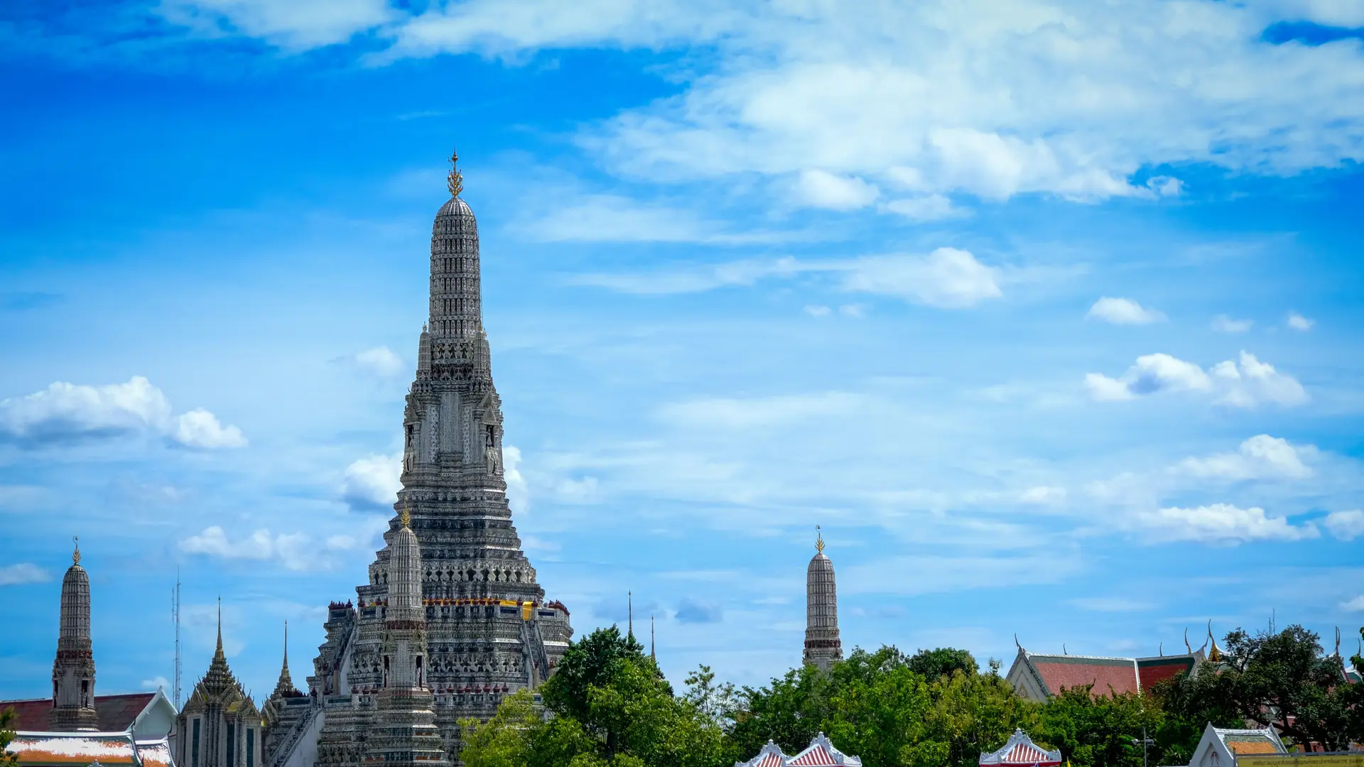 Wat Arun glowing beside the Chao Phraya River under a vivid Bangkok sky