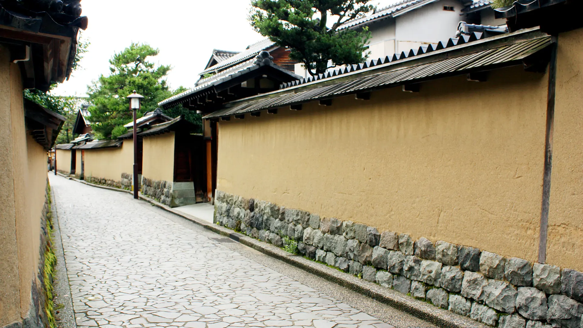 sunny earthen walls and stone lane in Kanazawa's Nagamachi Samurai District
