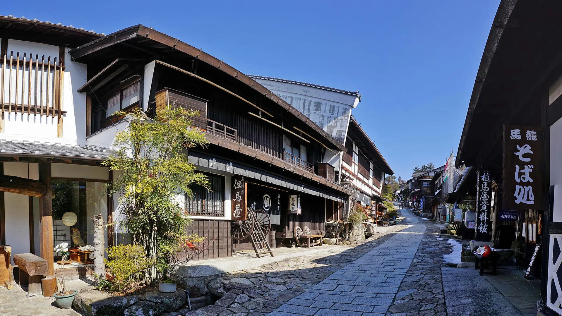 A preserved wooden post town street in rural Japan under warm morning sunlight