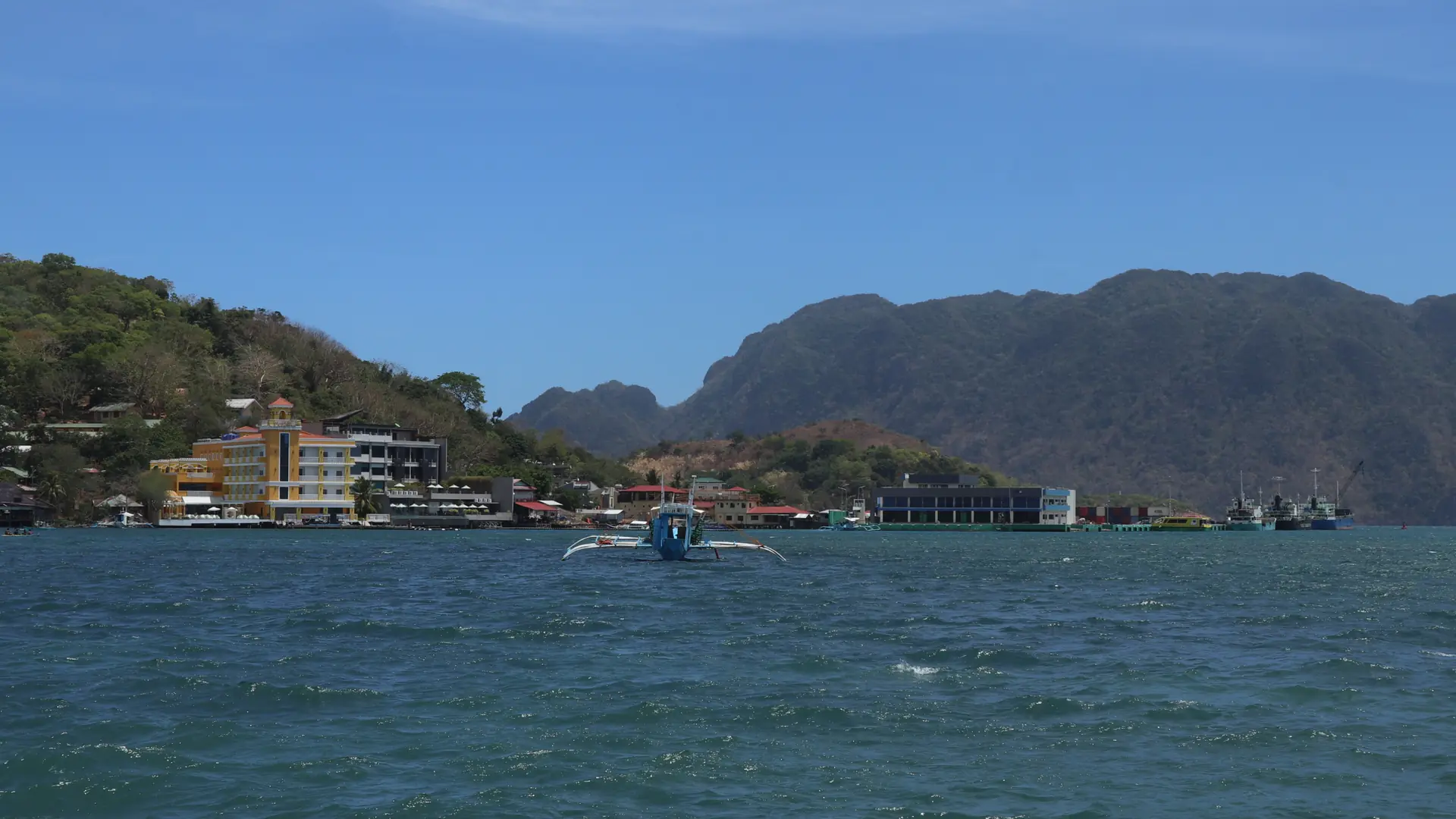 Waterfront buildings and moored bangkas beside Coron town’s blue bay