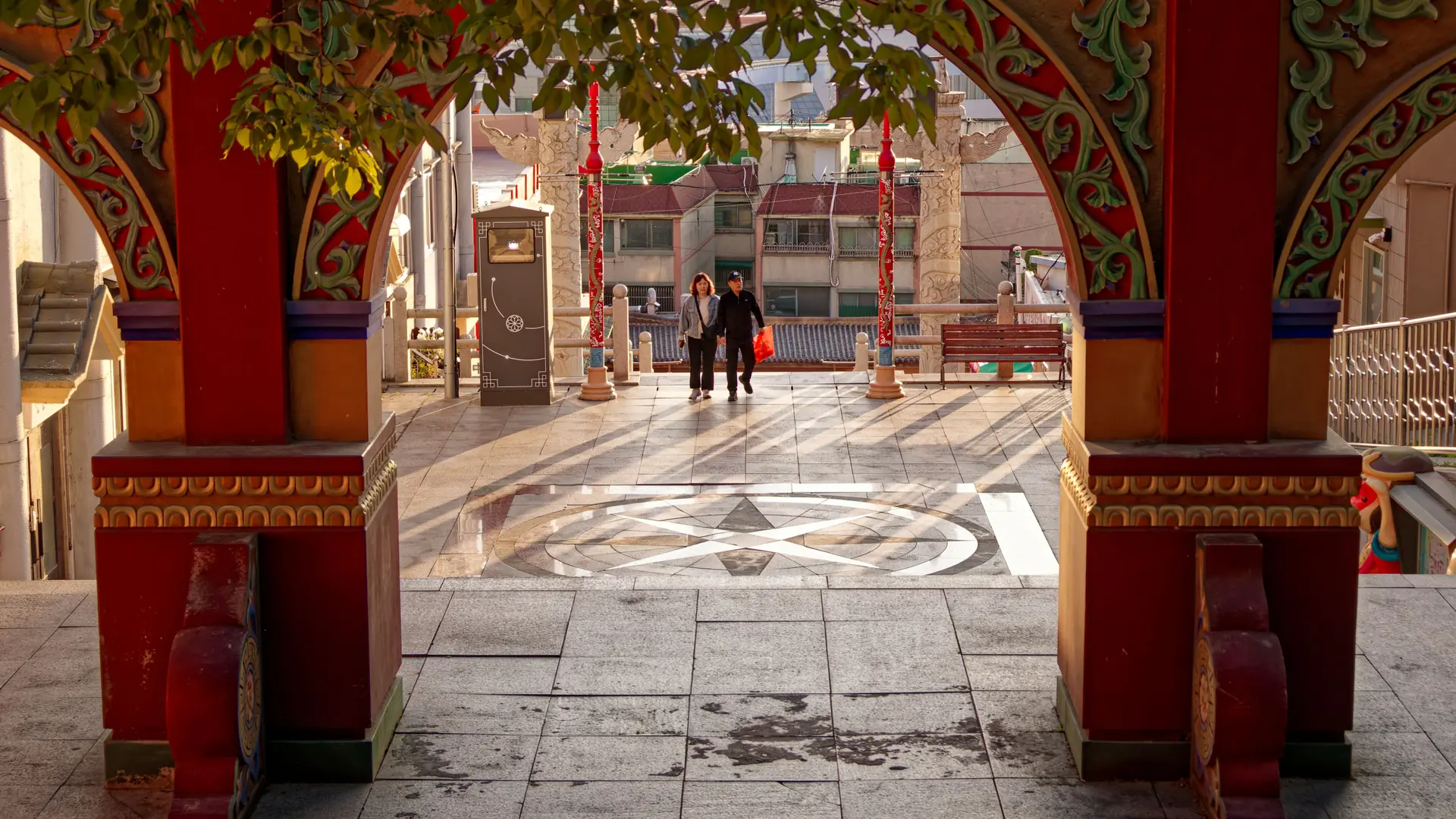 Incheon Chinatown's red archway and plaza with visitors walking through in daylight