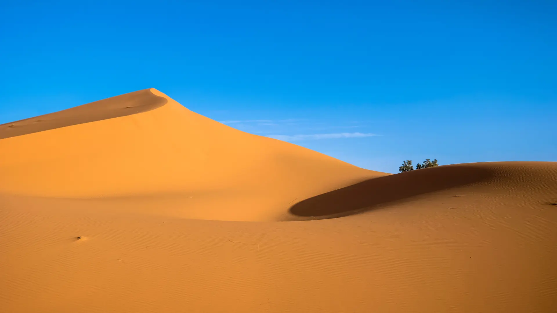 Orange dune near Ksar Tanamouste beneath a bright blue sky