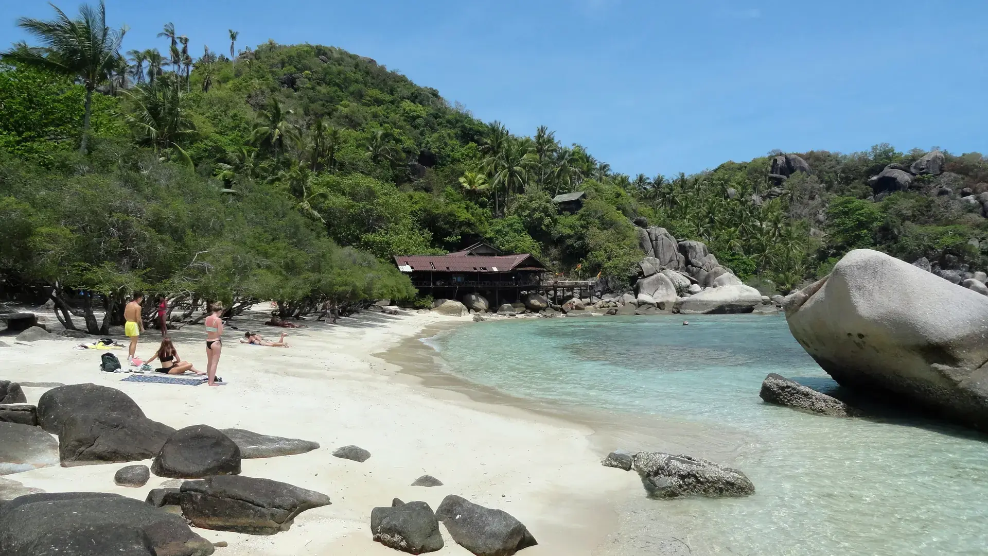 Granite boulders and sandy shore at Freedom Beach on Koh Tao, a wider island scene
