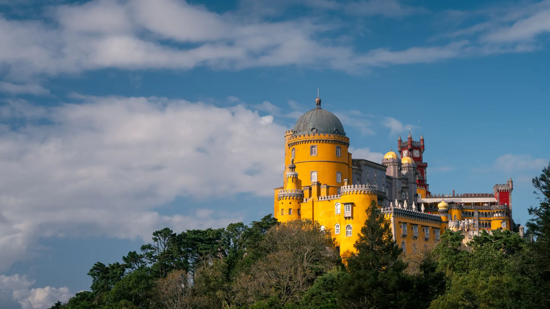 Colourful Pena Palace rising above the wooded Sintra hills on a sunny day
