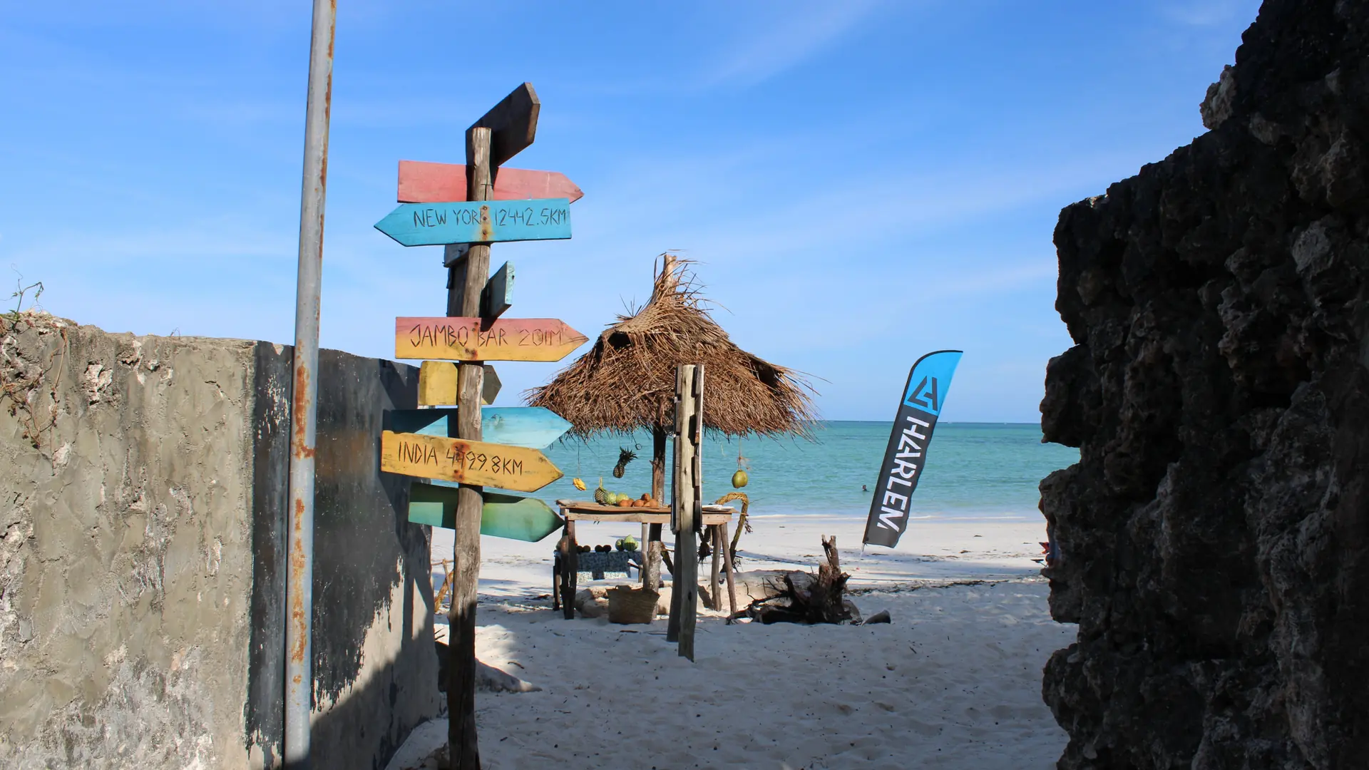 Colourful Paje Beach sign beside the sea beneath a blue sky