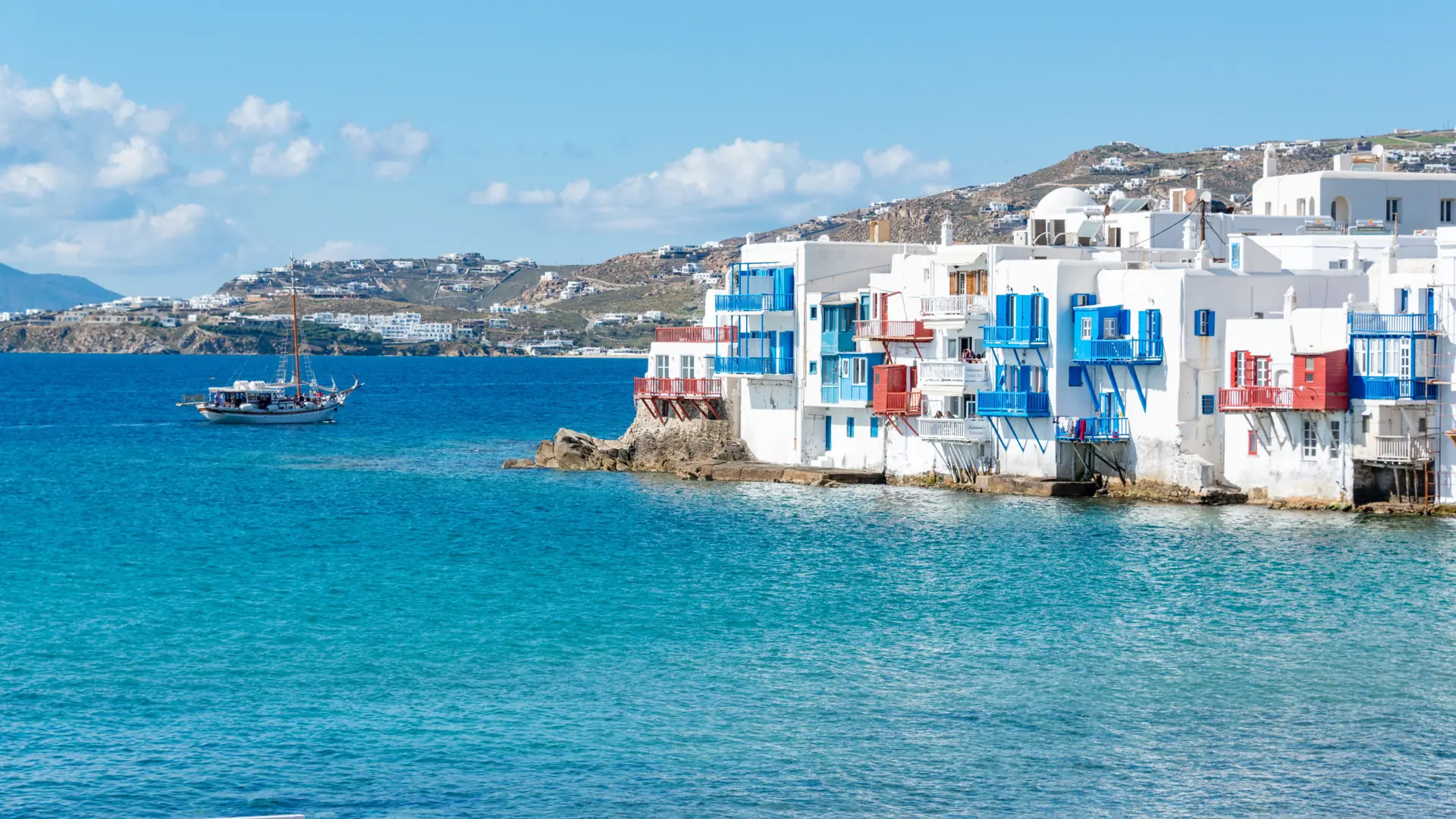 White waterfront houses with blue and red balconies at Little Venice in Mykonos in daylight