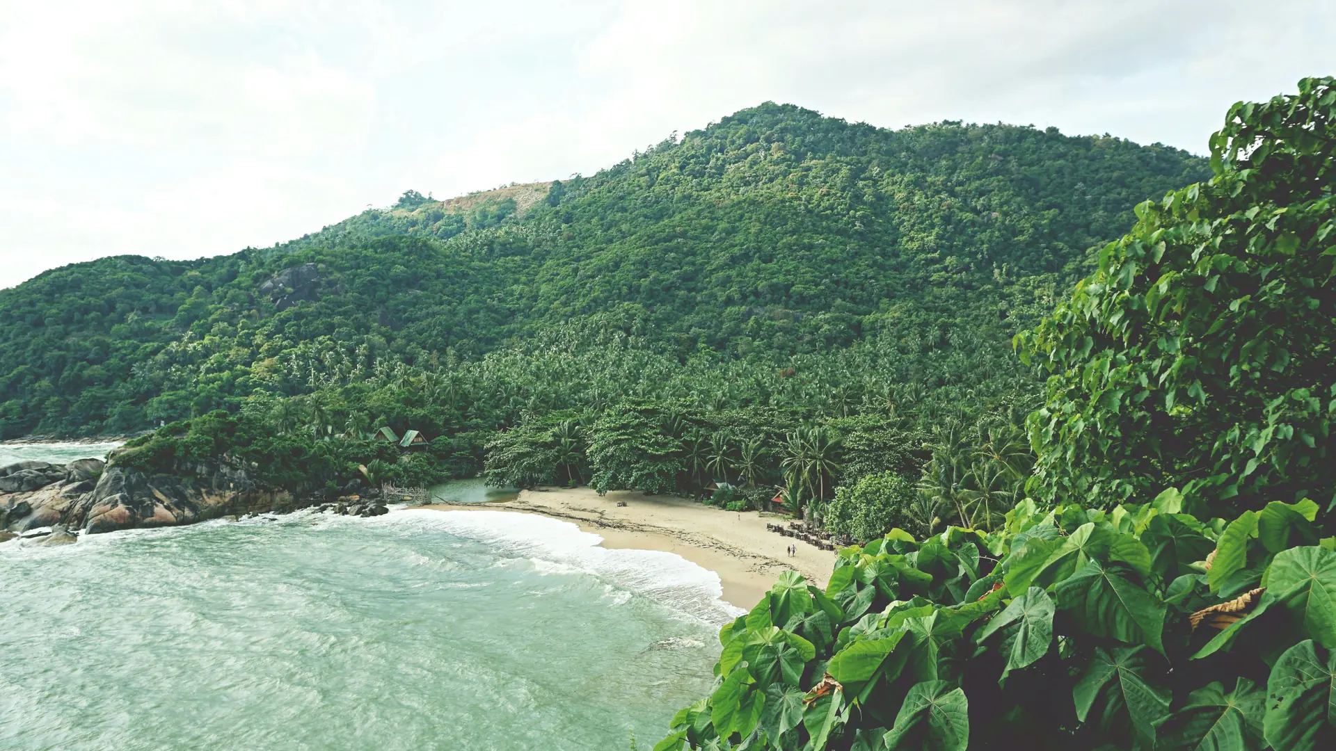A quiet crescent of sand below green hills on Koh Phangan