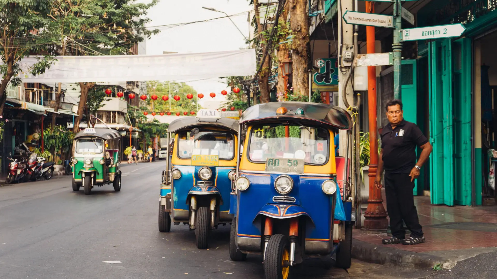 Colourful tuk-tuks on Charoen Krung Road in Bangkok, a wider city scene