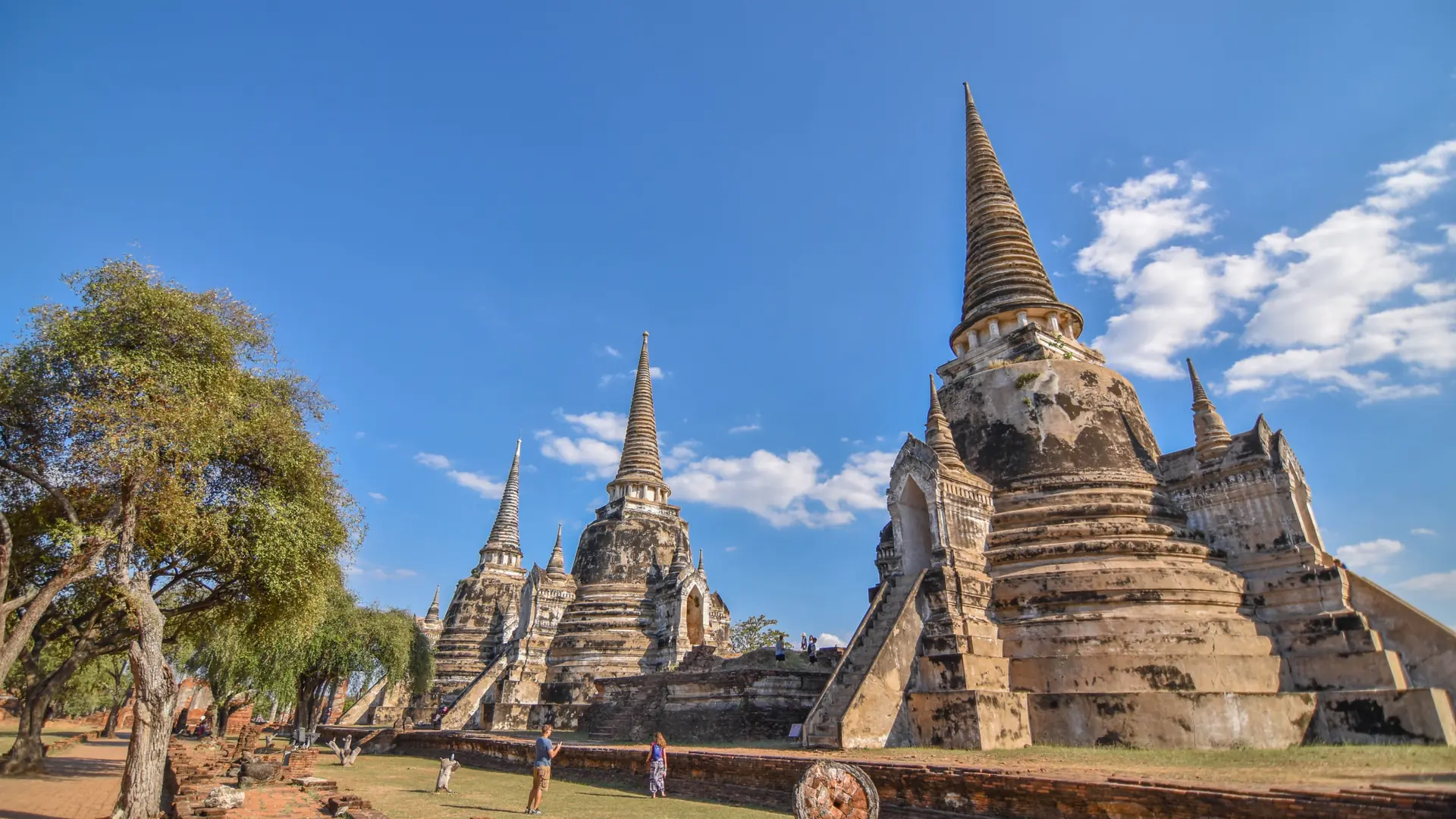 An ancient Ayutthaya pagoda standing against a vivid blue sky