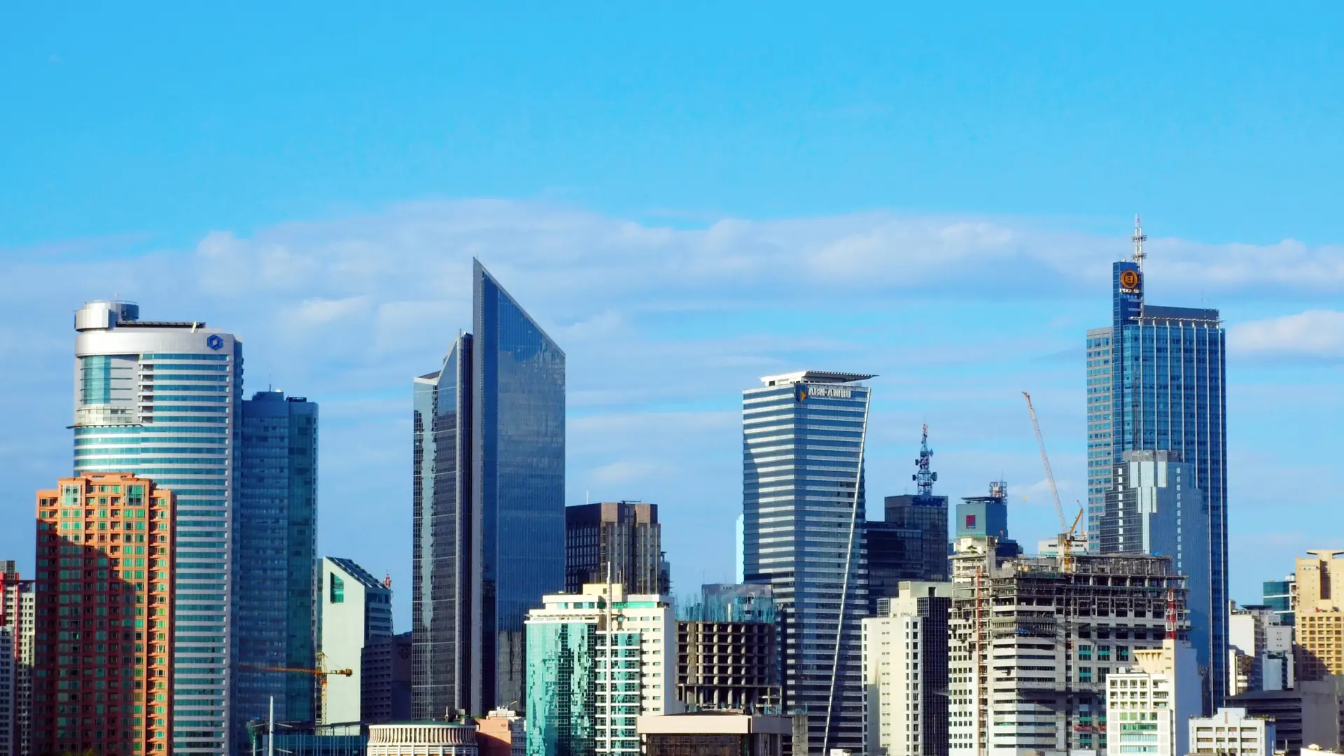 Glass towers of the Makati skyline under a deep blue sky in Metro Manila