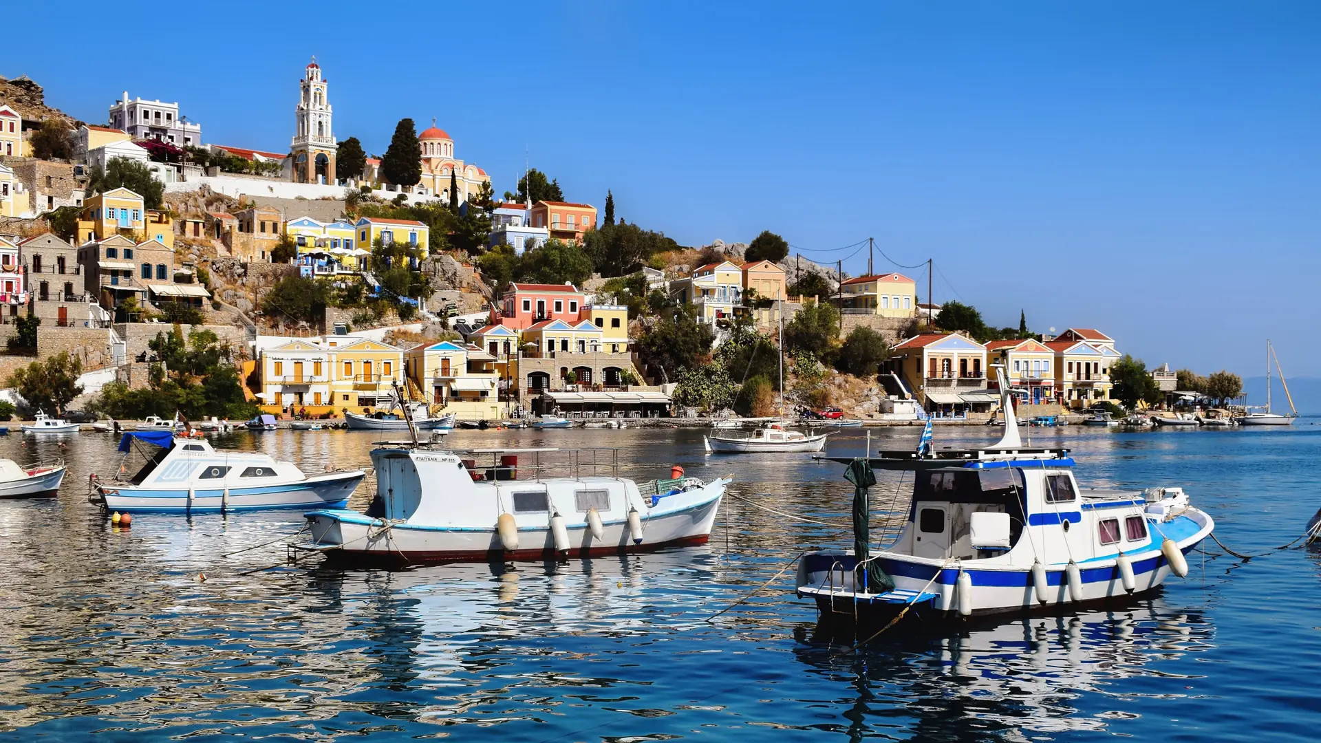 Fishing boats in Gialos harbour below Symi’s colourful waterfront houses