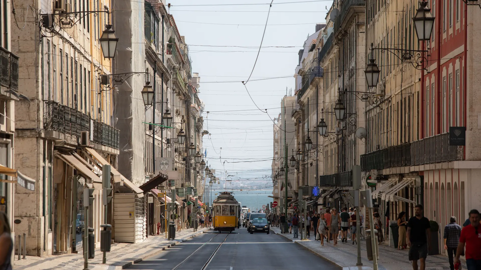 Yellow tram climbing a narrow tiled street in Lisbon