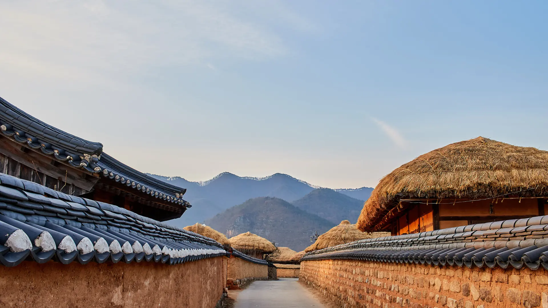 Hahoe Folk Village's traditional houses beside the Nakdong River in Andong, under a bright sky