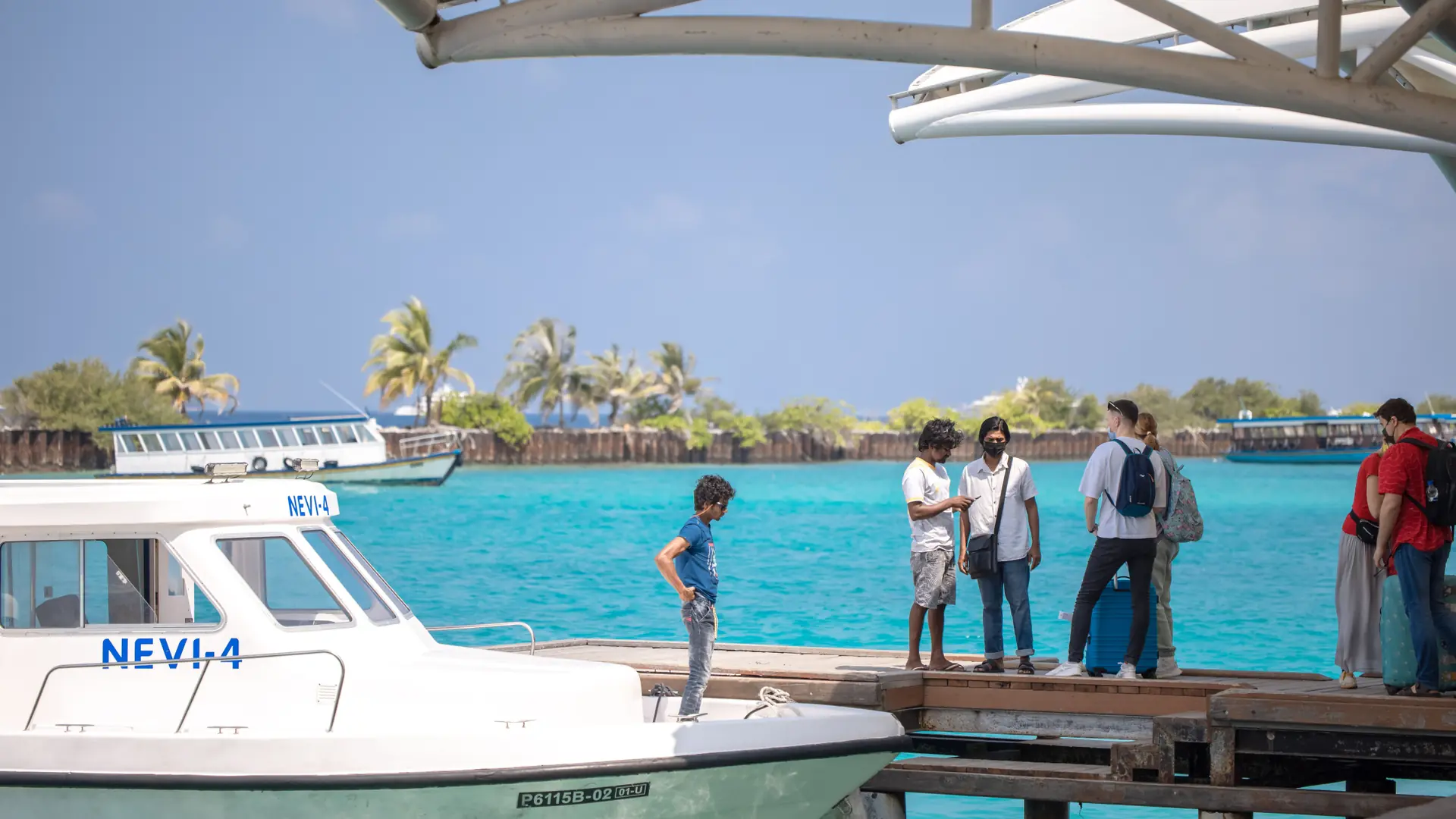 Travellers boarding a boat from a sunny Maldivian island jetty