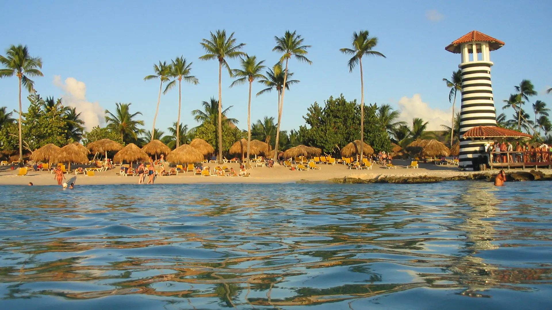 Sunny Playa Dominicus beach and striped lighthouse beside the resort shore