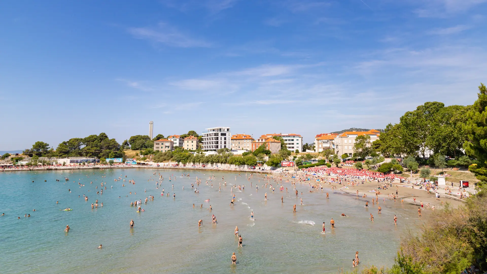 Bright Bačvice beach with shallow turquoise water and Split’s waterfront beyond