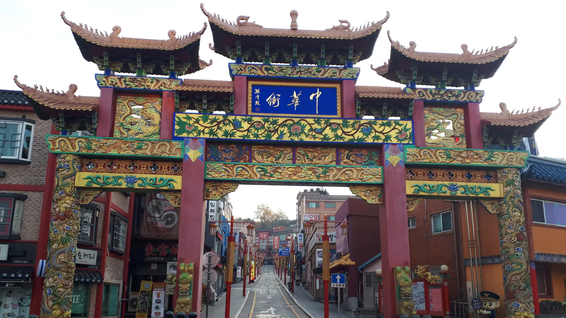 Incheon Chinatown's ornate main gate reading '中華街' (Chinatown Street) above the entrance to the district, under a bright sky