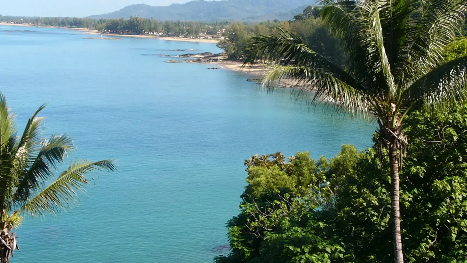 Palm-framed rocky shoreline and turquoise water on the Khao Lak coast