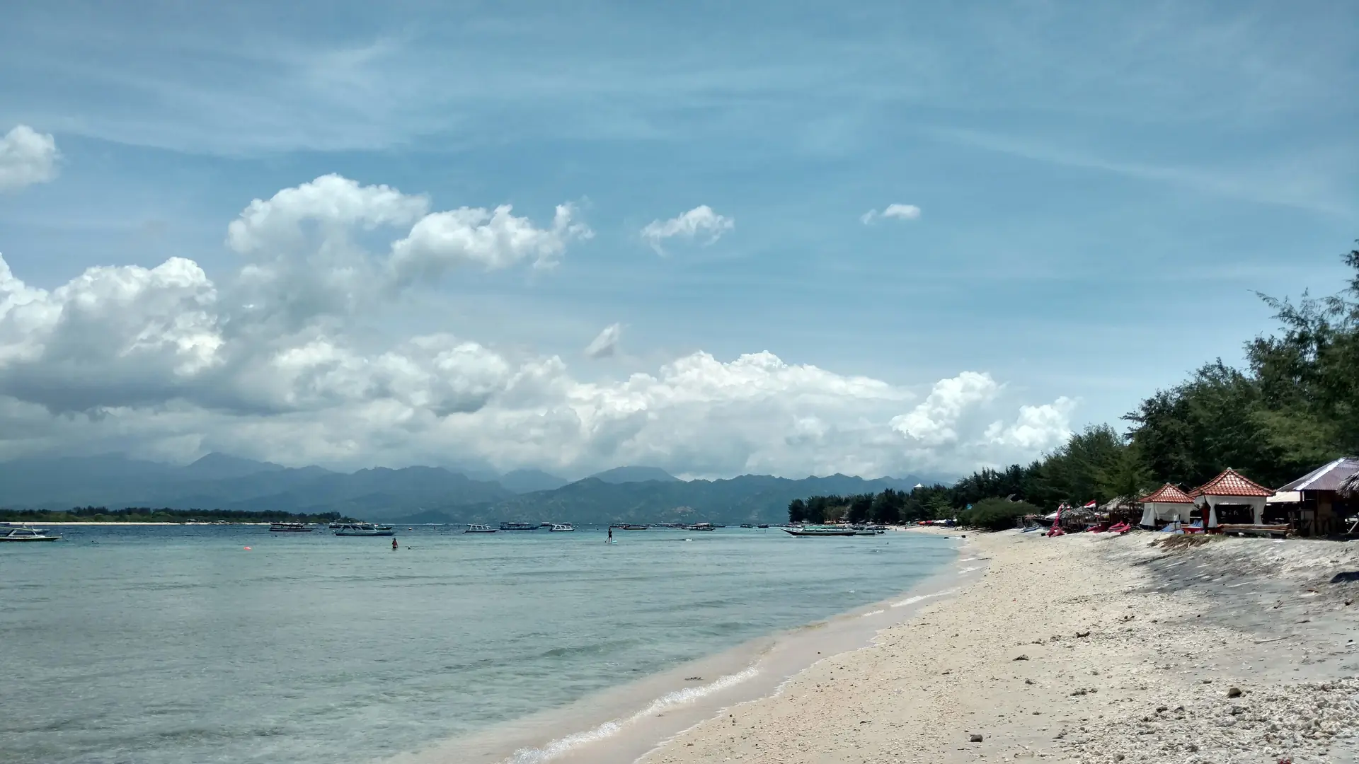 Pale beach, small boats and low beachfront buildings near Blue Star Bar on northern Gili Trawangan