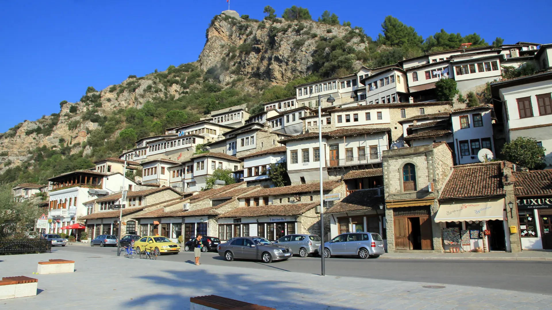 Berat's Mangalem quarter of white Ottoman houses climbing the castle hill under a deep blue sky
