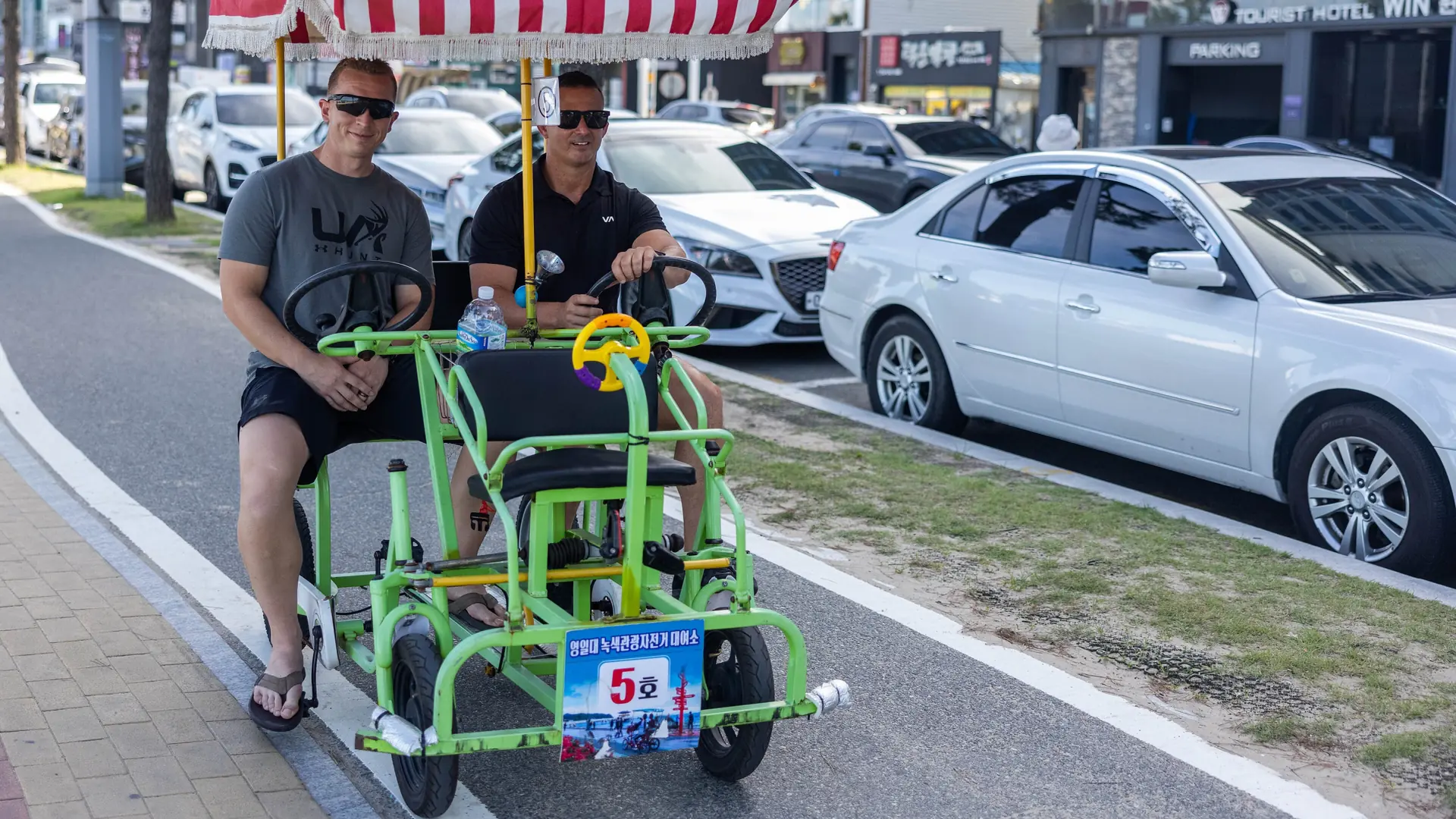 A four-wheeled rental bike labelled for Yeongildae's green tourism route along the Pohang beachfront in bright daylight