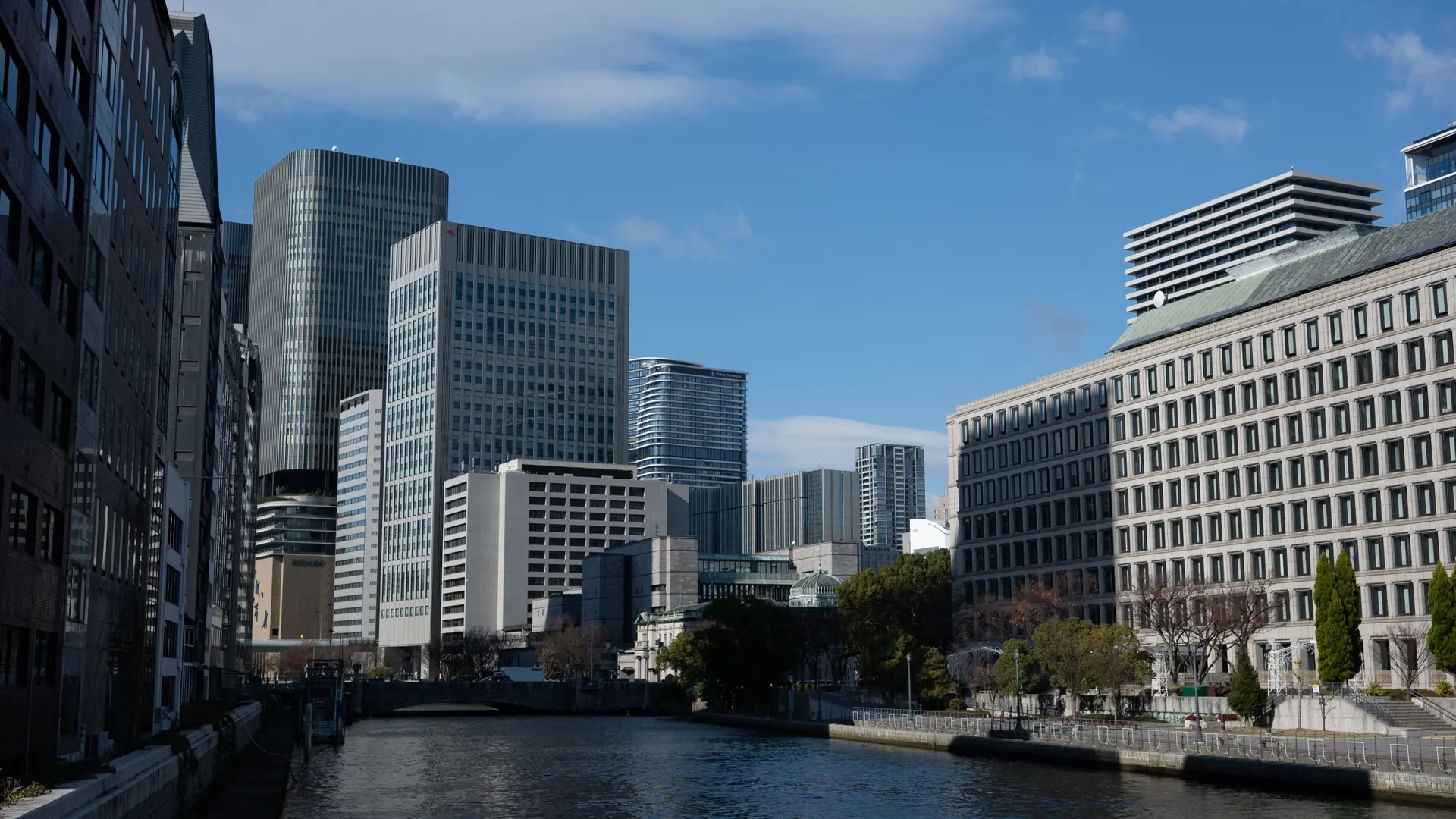 Daylight on Osaka’s riverfront promenade, with office buildings and a blue sky