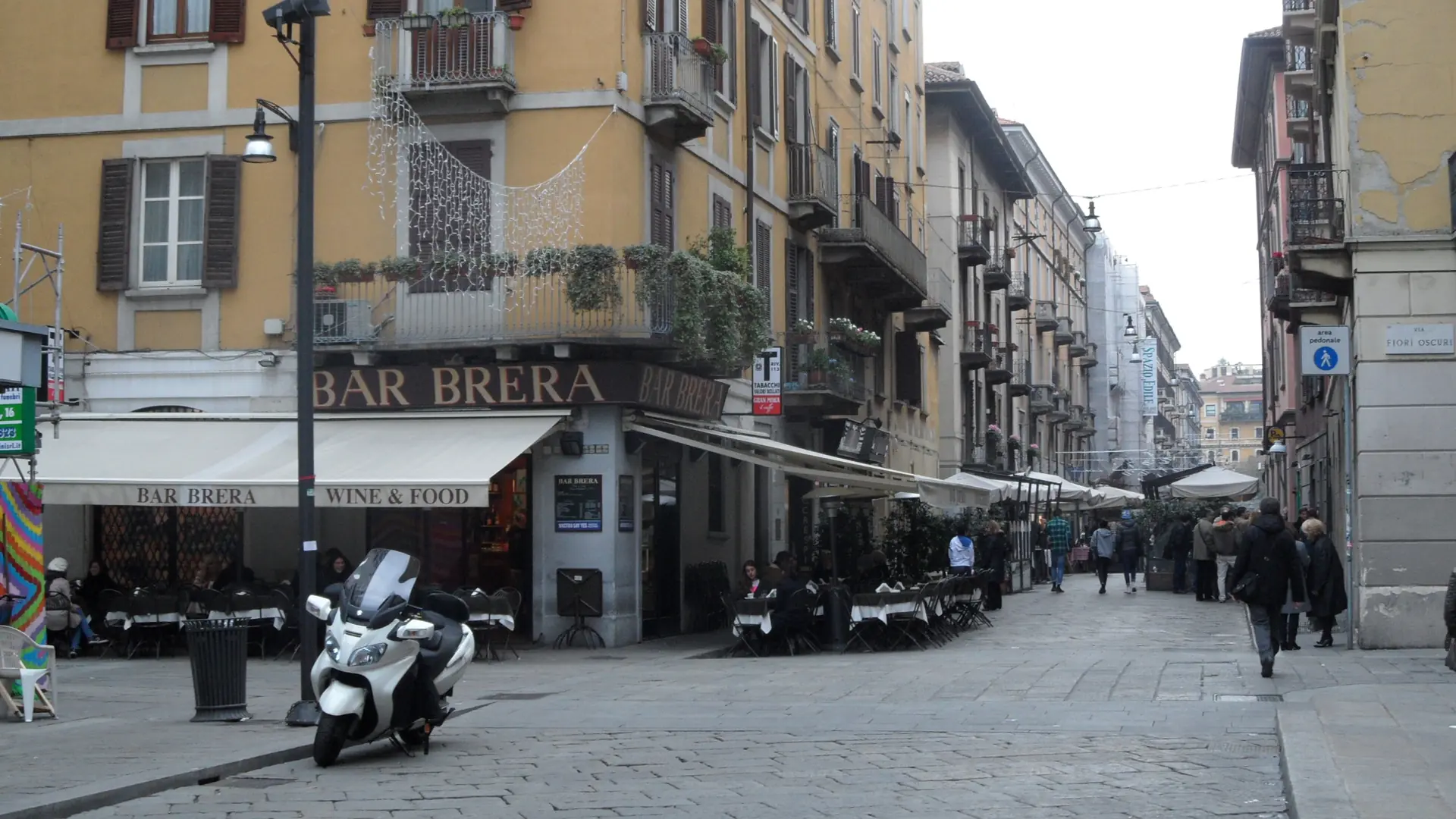 ochre facades and cafe tables along a cobbled street in Milan's Brera district
